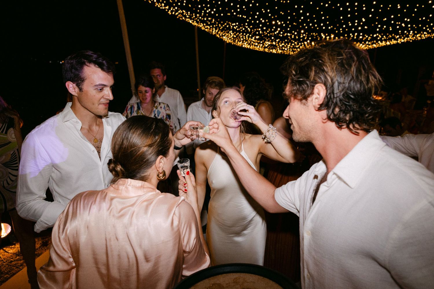 a bride and guests doing shots during the open-air wedding party of their Spetses wedding