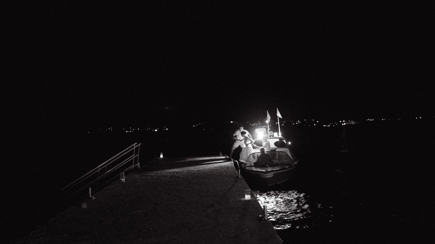 a black and white night photo of a boat at sea that just brought the bride and groom to their wedding party