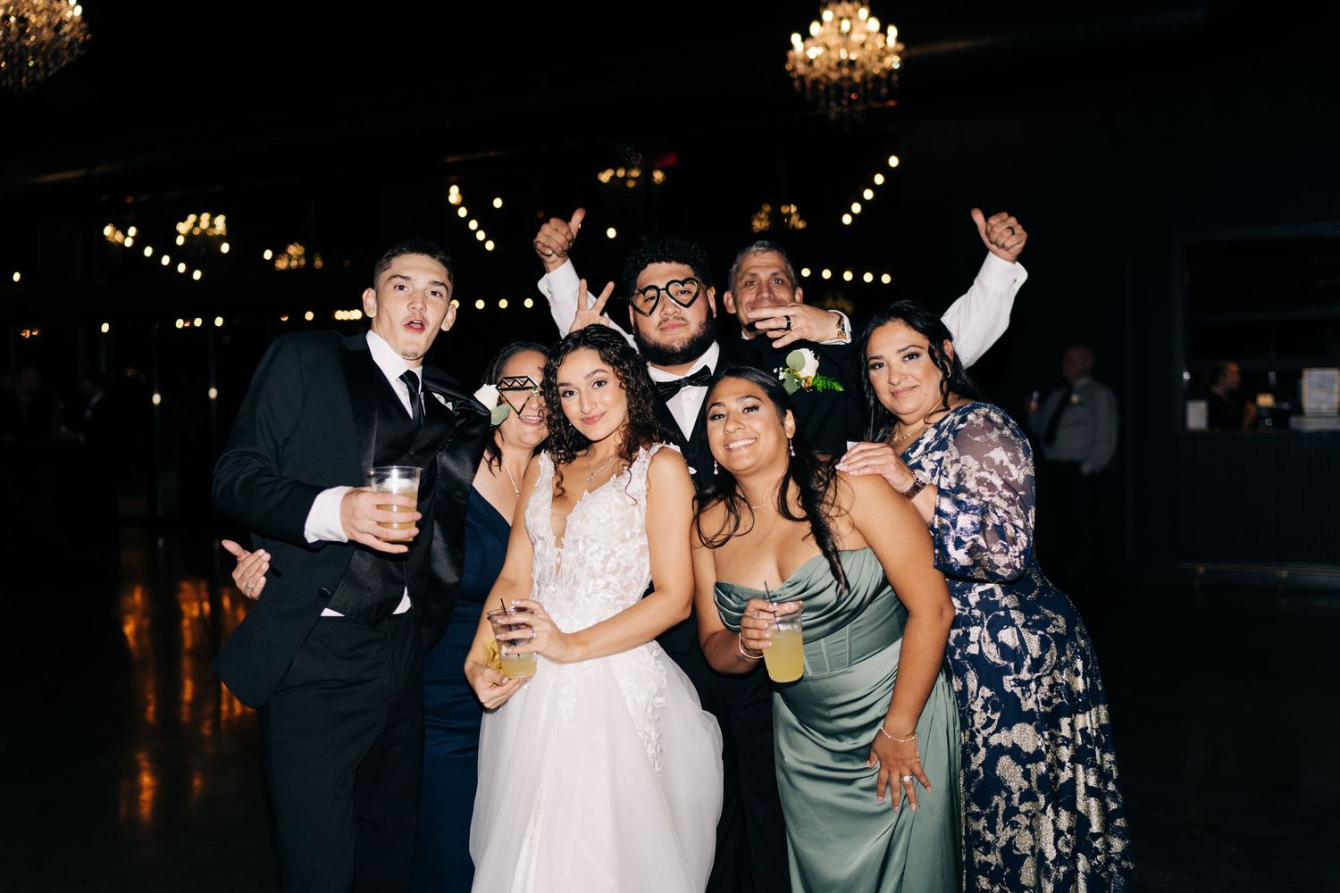 Bride and groom celebrate with wedding guests on the dance floor at reception.