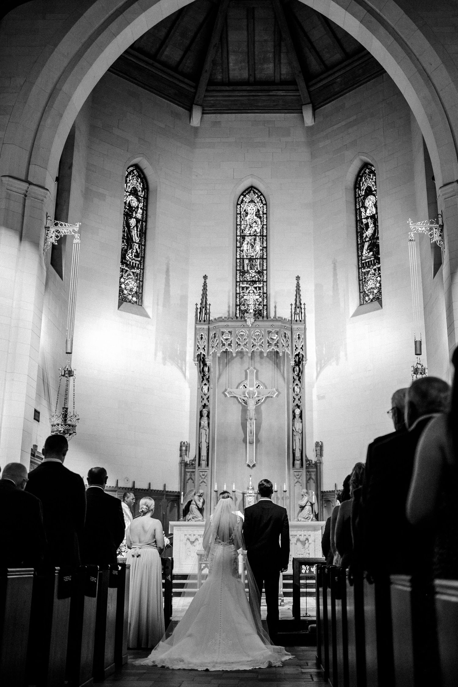 Black and white photo of bride and groom at church altar during wedding ceremony.