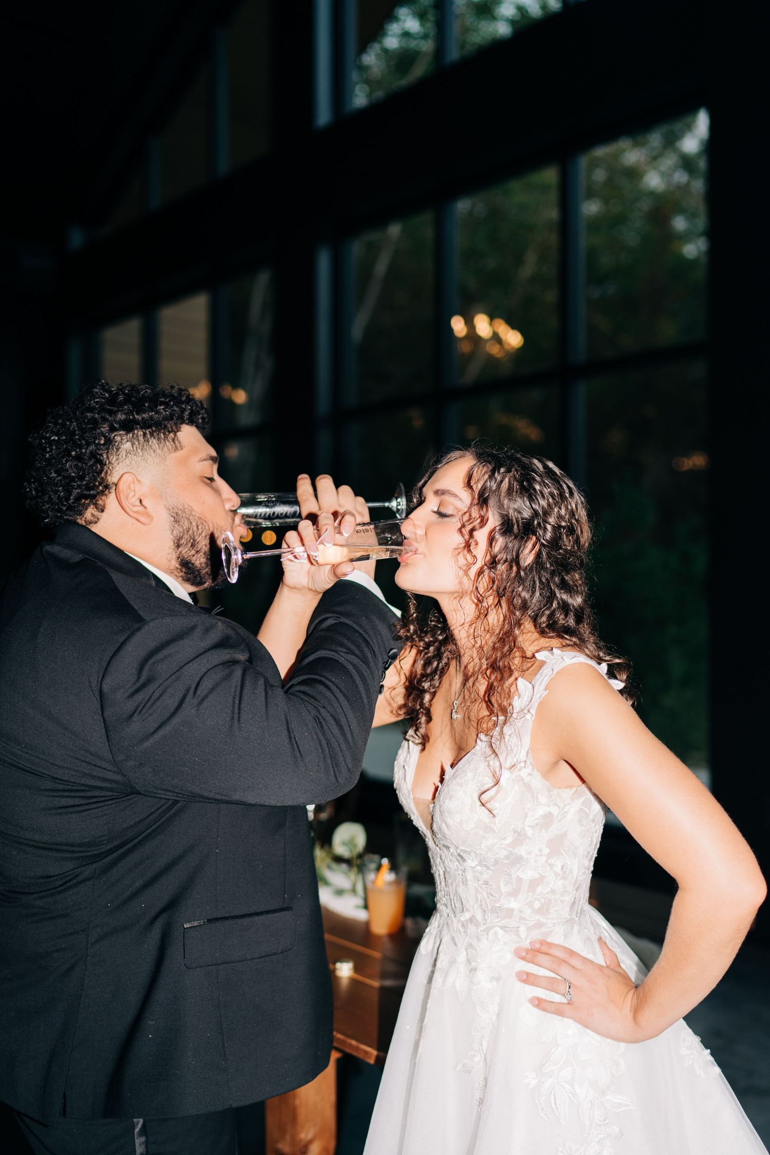 Bride and groom sharing a playful champagne toast at their elegant indoor wedding reception.