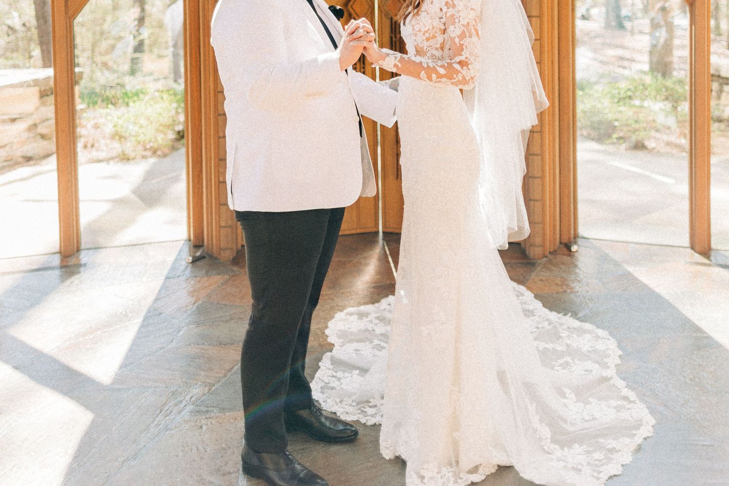 Bride and groom exchanging vows under wooden gazebo during outdoor wedding ceremony.