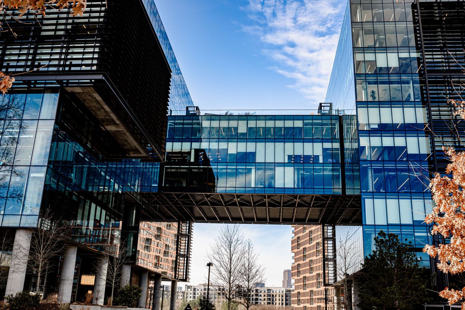 Modern glass office buildings with reflective windows against a blue sky in an urban setting.