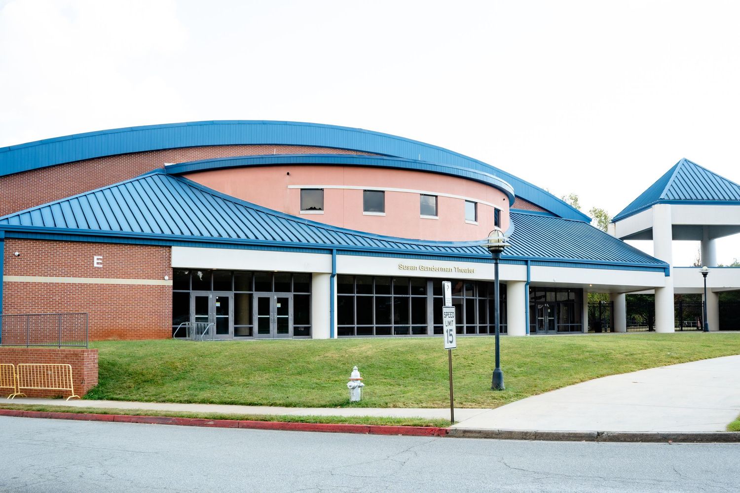 Exterior view of a modern brick school building with blue roof trim and walkways.