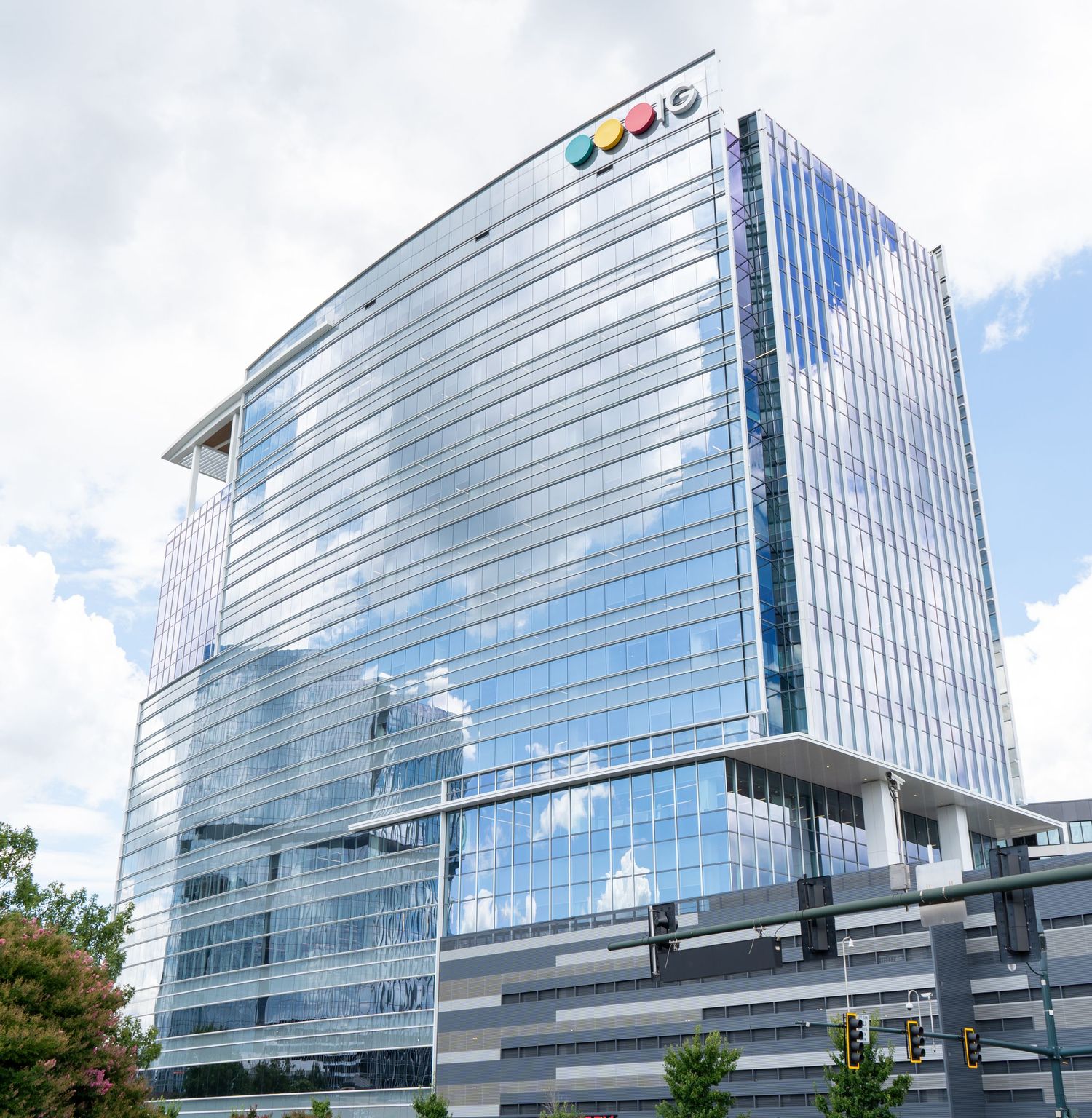 Modern glass office building with reflective blue windows and angular architecture shown from multiple angles in daylight.
