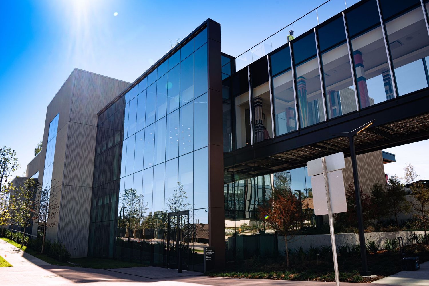 Modern office building exterior with glass walls and reflective windows on a sunny day.