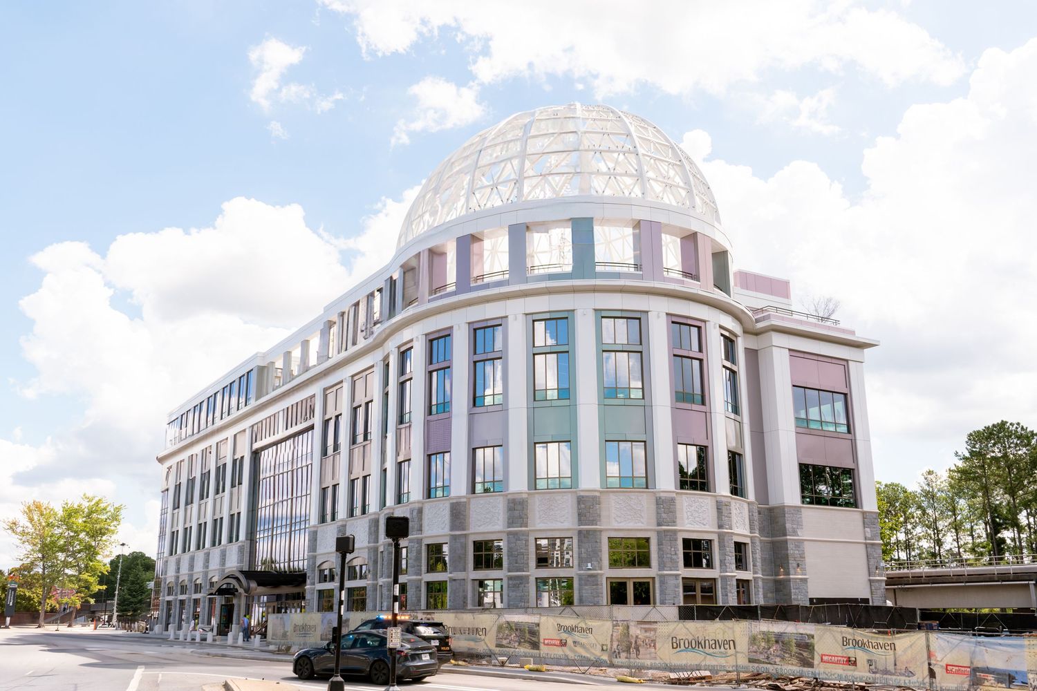 A panoramic view of a modern commercial office building complex with glass windows and white exterior under blue sky.
