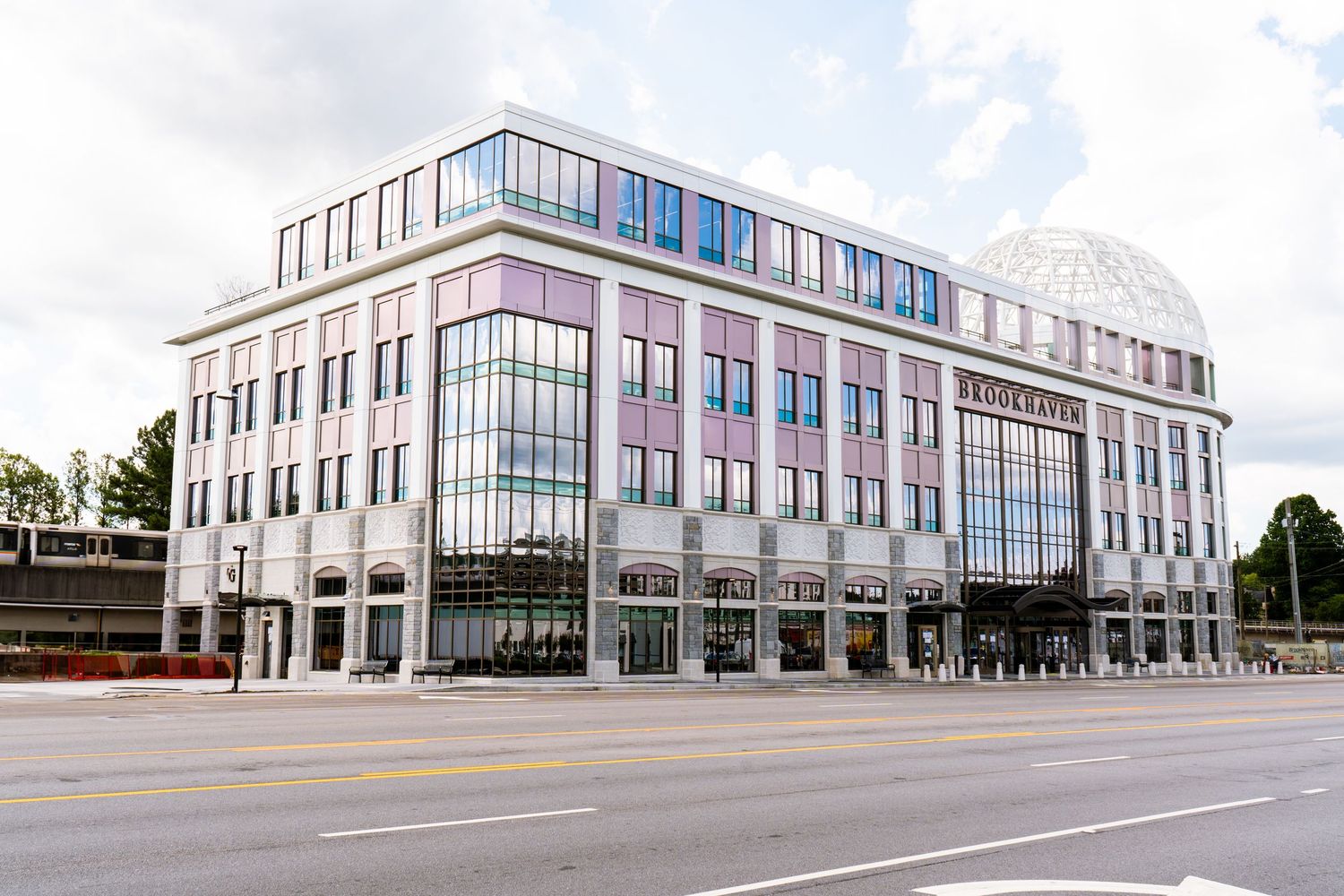 Modern commercial building with glass windows and white exterior shown from multiple angles on a cloudy day.