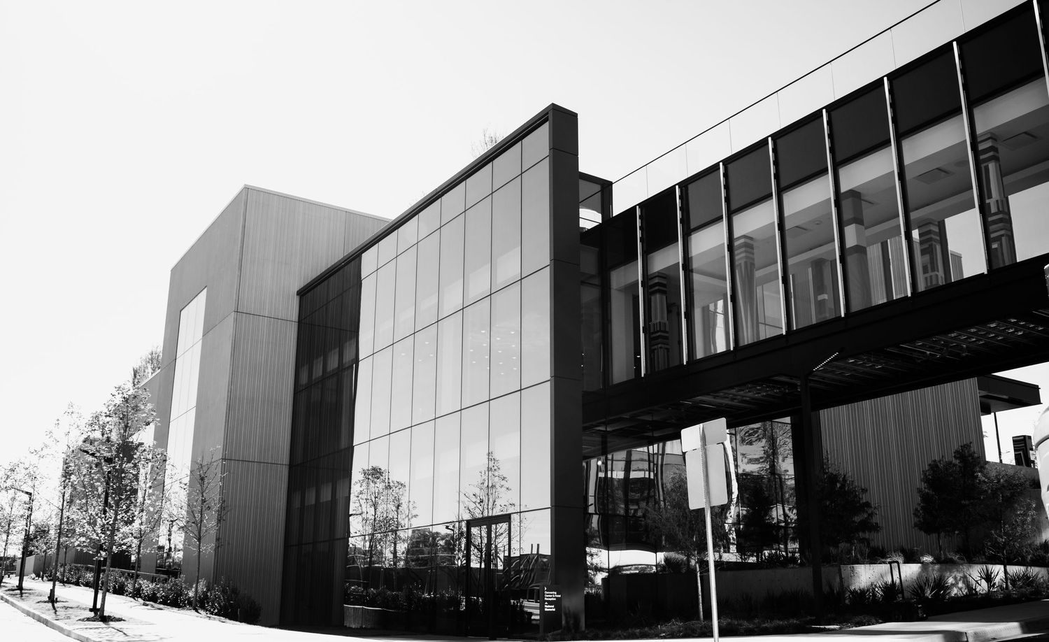 Modern office building facade with angular glass panels and geometric lines shown in black and white panoramic view.