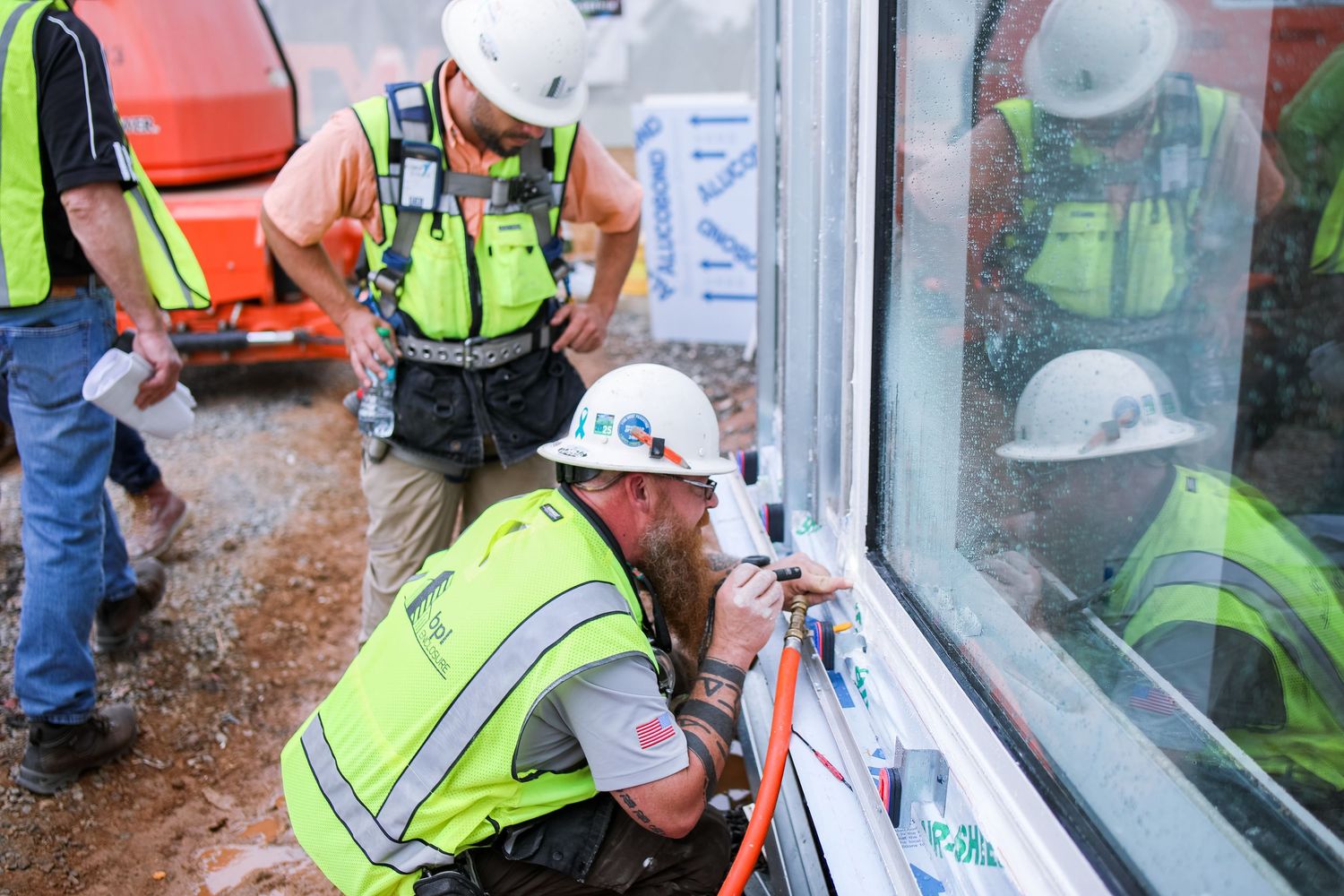 Workers in safety gear installing commercial windows on construction site.