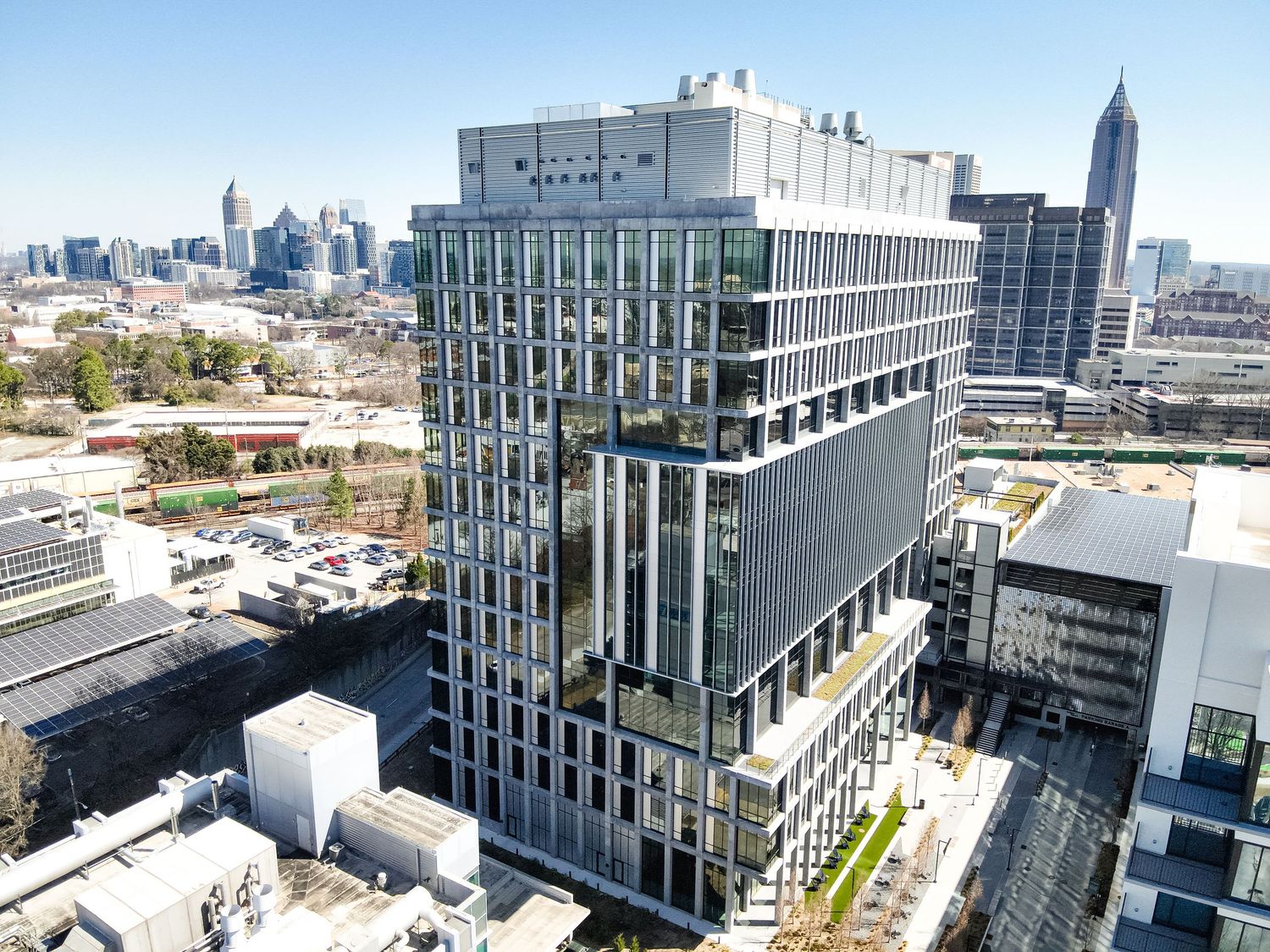 Aerial view of a modern glass office tower in Atlanta, GA, with city skyline visible in the background on a clear day.