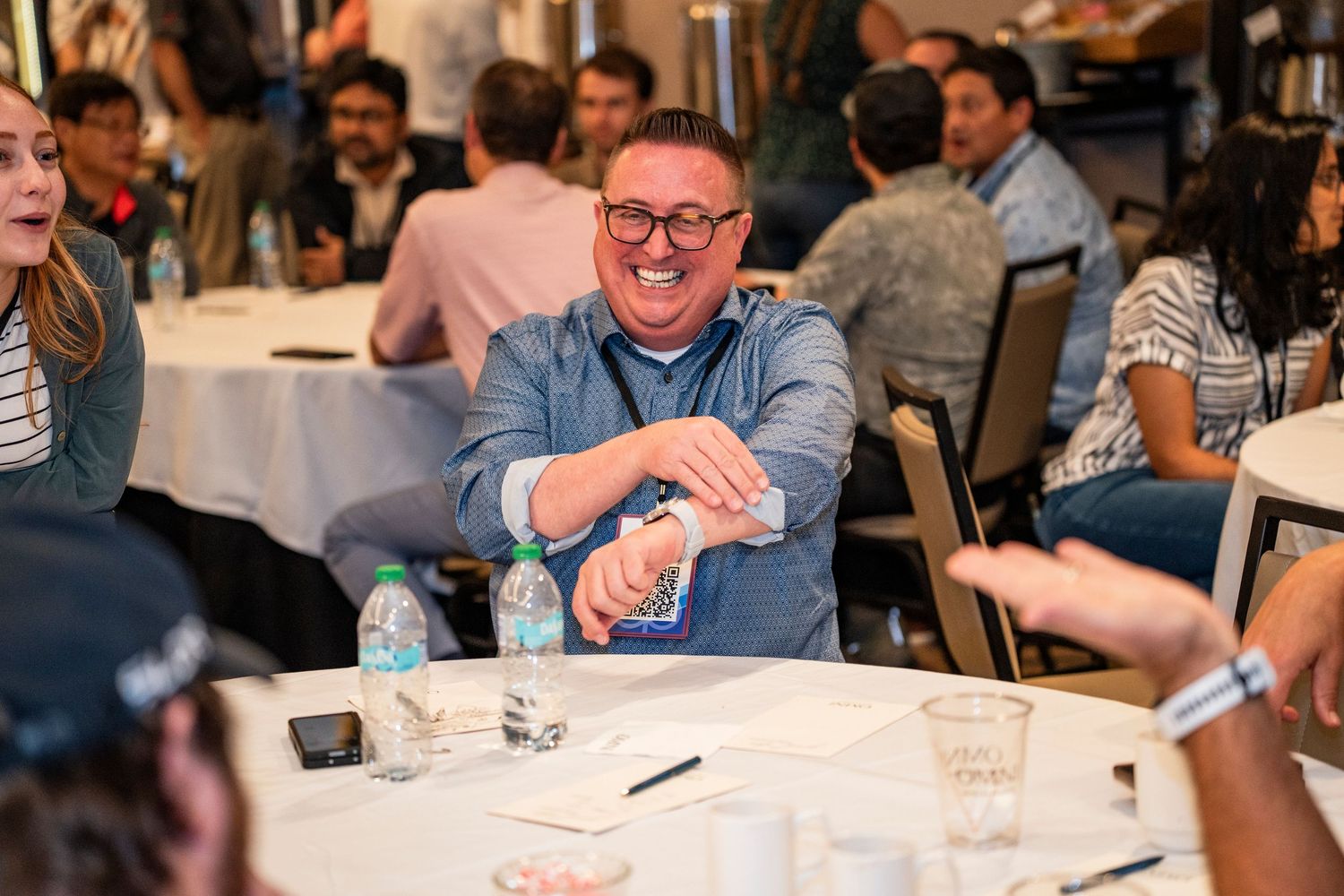 People sitting at tables and enjoying drinks at a crowded social gathering or networking event.