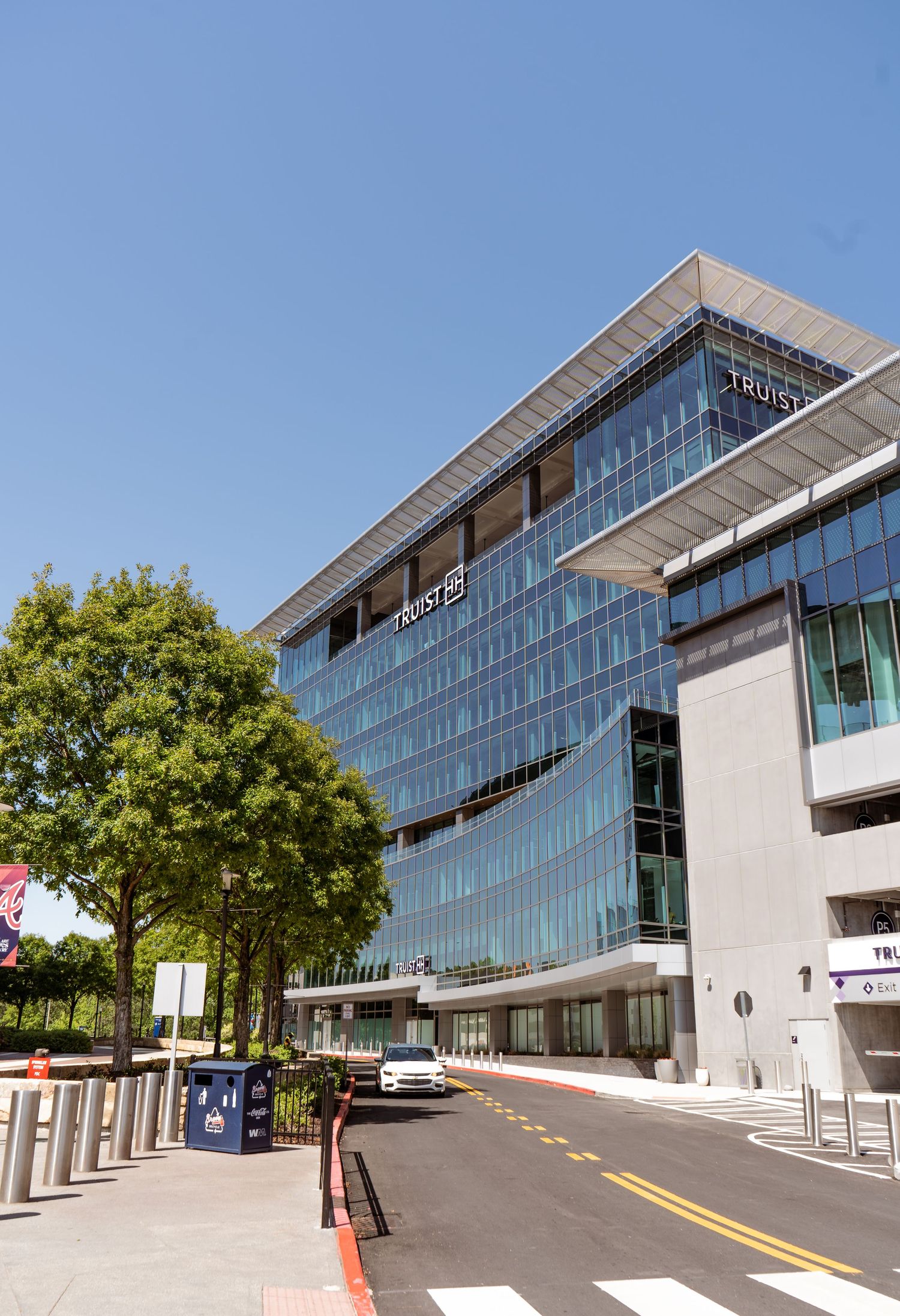 Modern glass office building exterior with sloped architecture and curved facade design under blue sky.