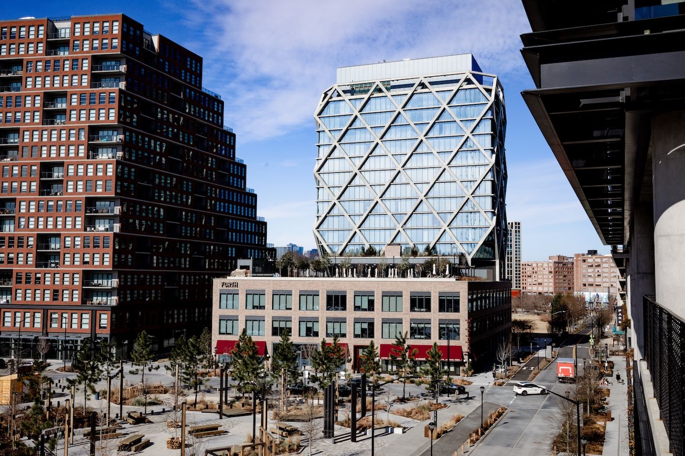 Urban streetscape with brick buildings and glass structures creating interesting architectural contrasts.