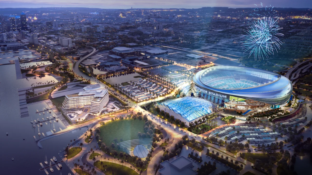 Aerial night view of a modern sports complex with a glowing stadium, fireworks, and waterfront cityscape.