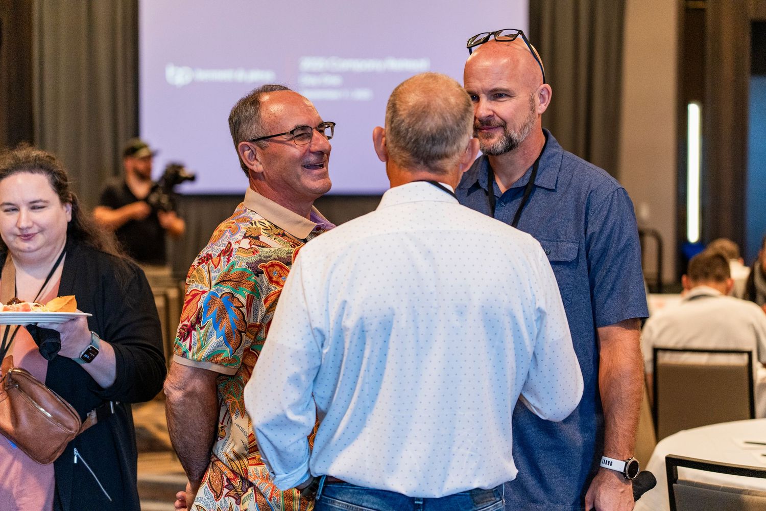 Three people engaged in animated conversation at an indoor business networking event.