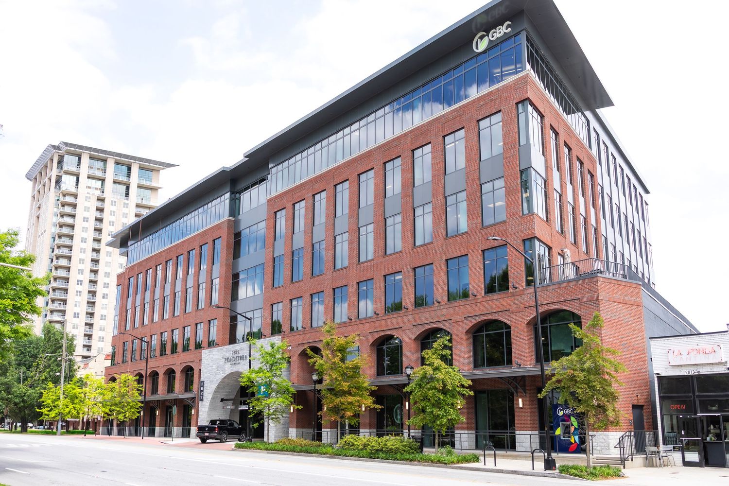 Modern brick office building with glass windows and angular architecture shown from multiple exterior angles.