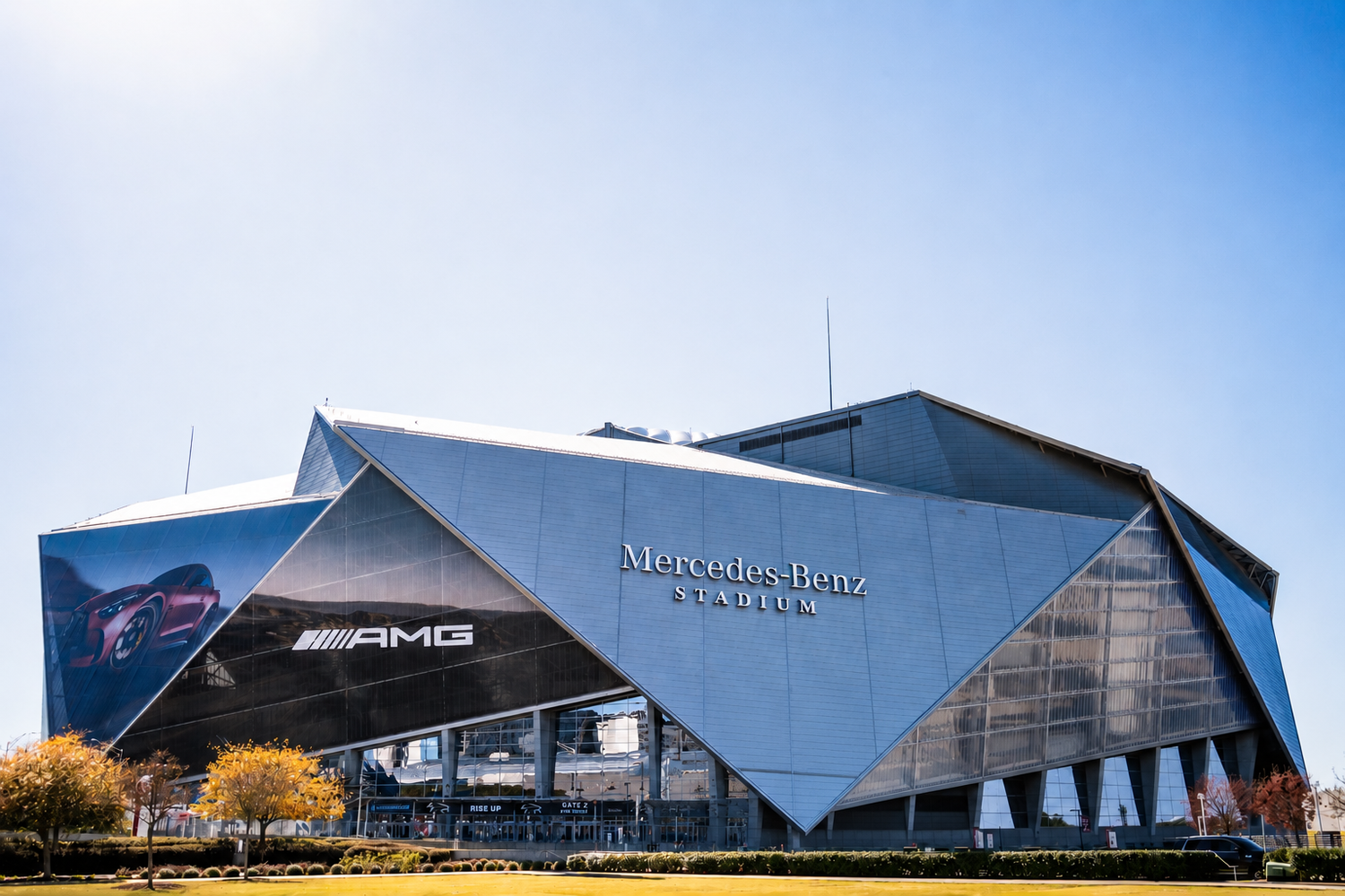 Mercedes-Benz Stadium, home of the Atlanta Falcons, features a striking geometric facade under a clear blue sky.