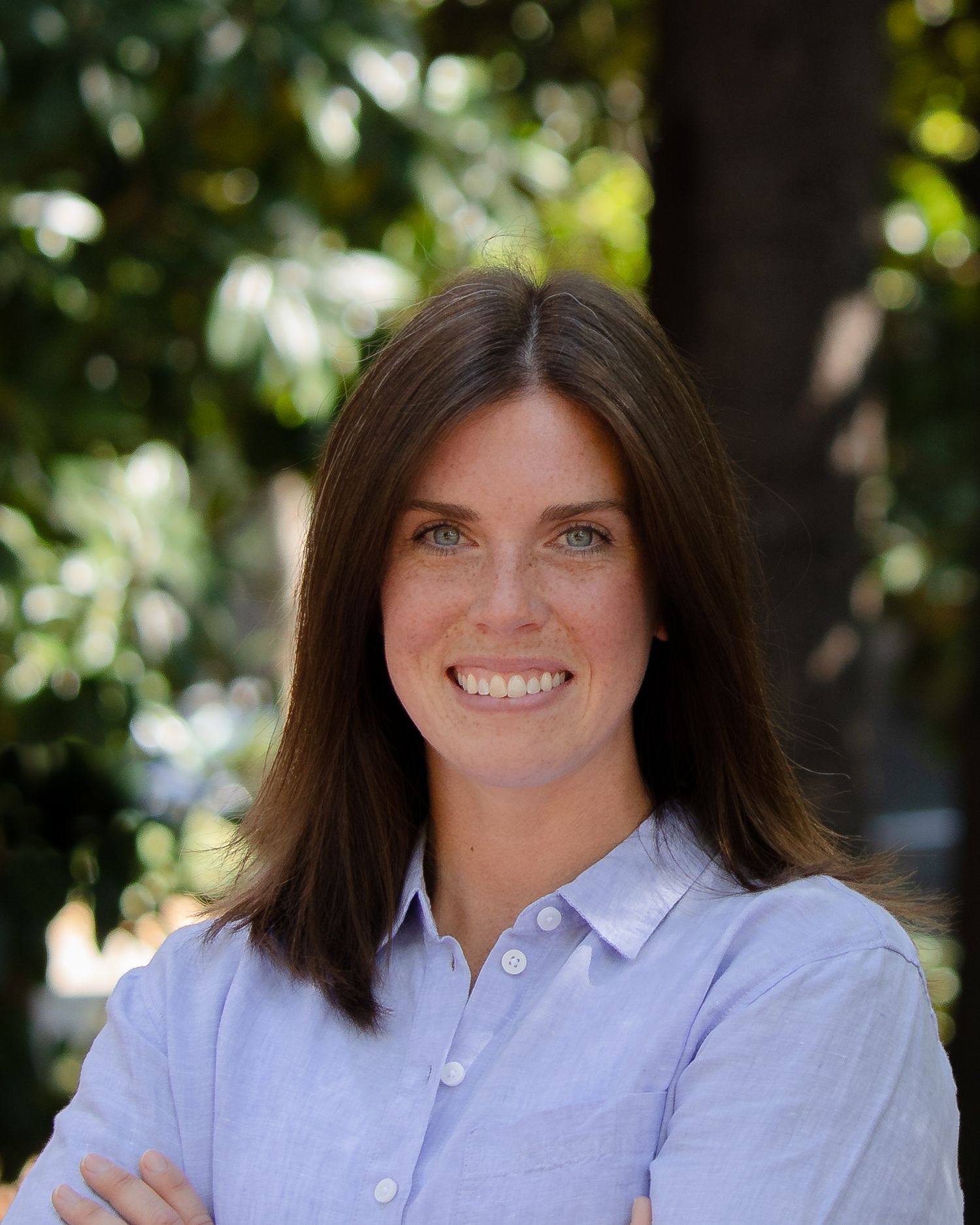 Professional headshot series showing same person in light blue button-down shirt against natural outdoor background.