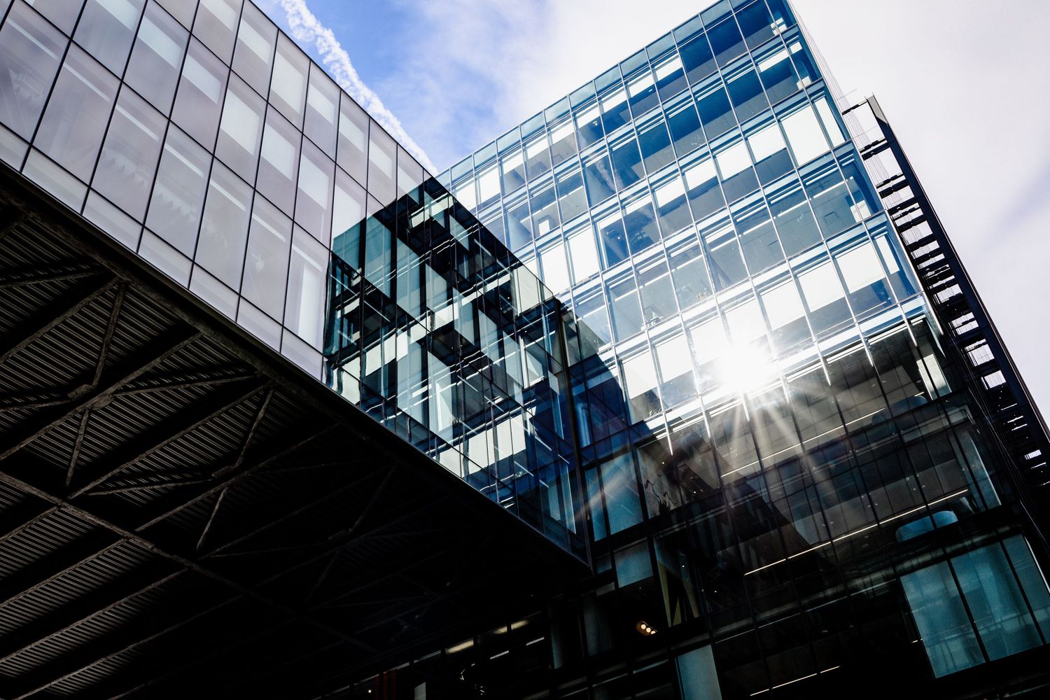 Modern glass office building facade with reflective windows and geometric patterns photographed from multiple angles.