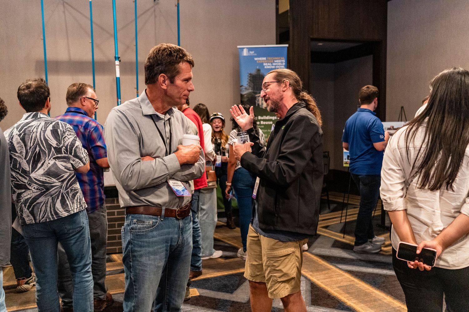 People gather and network at an indoor professional event with groups engaged in conversation throughout the space.