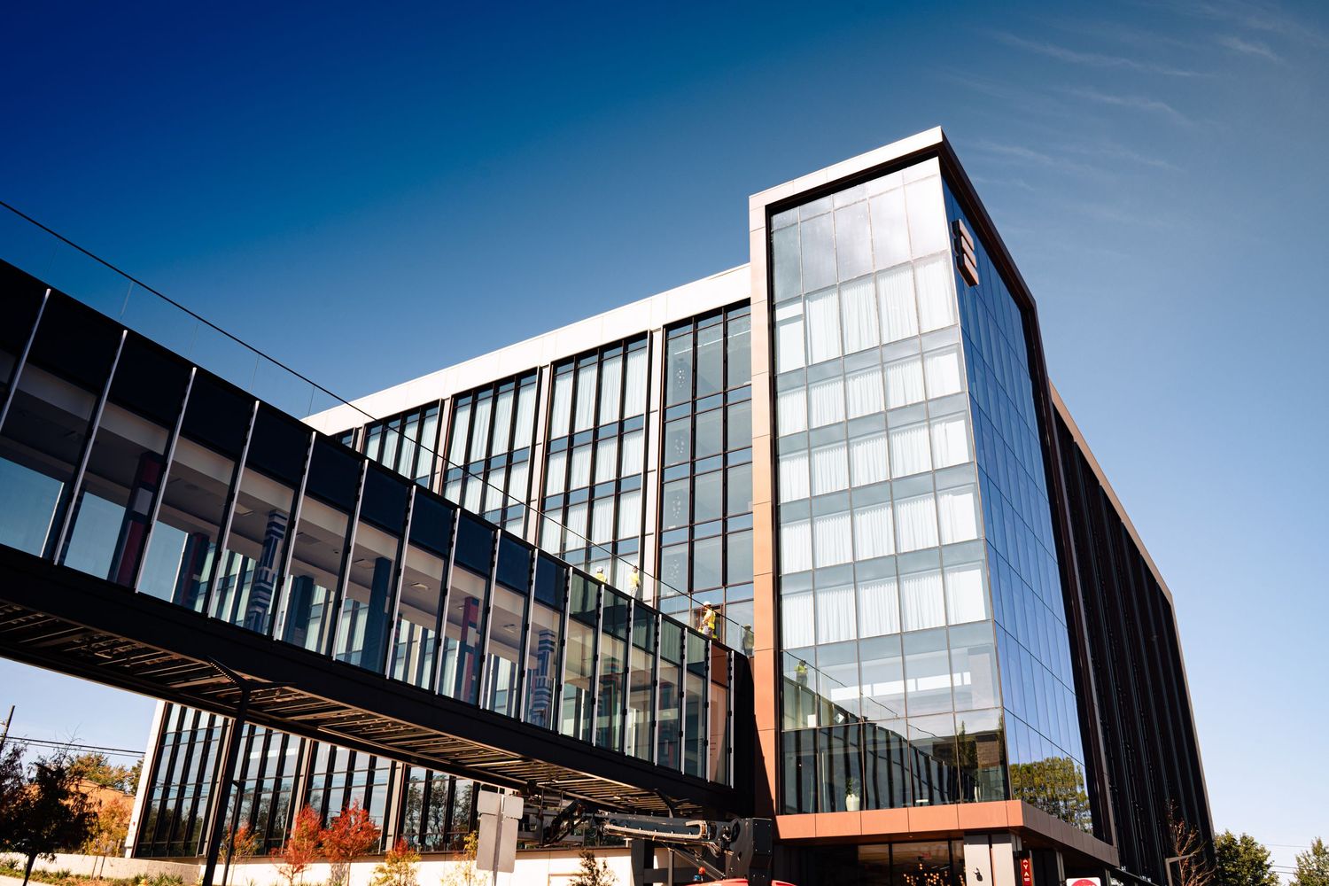 Modern office building with glass facade and angular architecture photographed from multiple angles against blue sky.