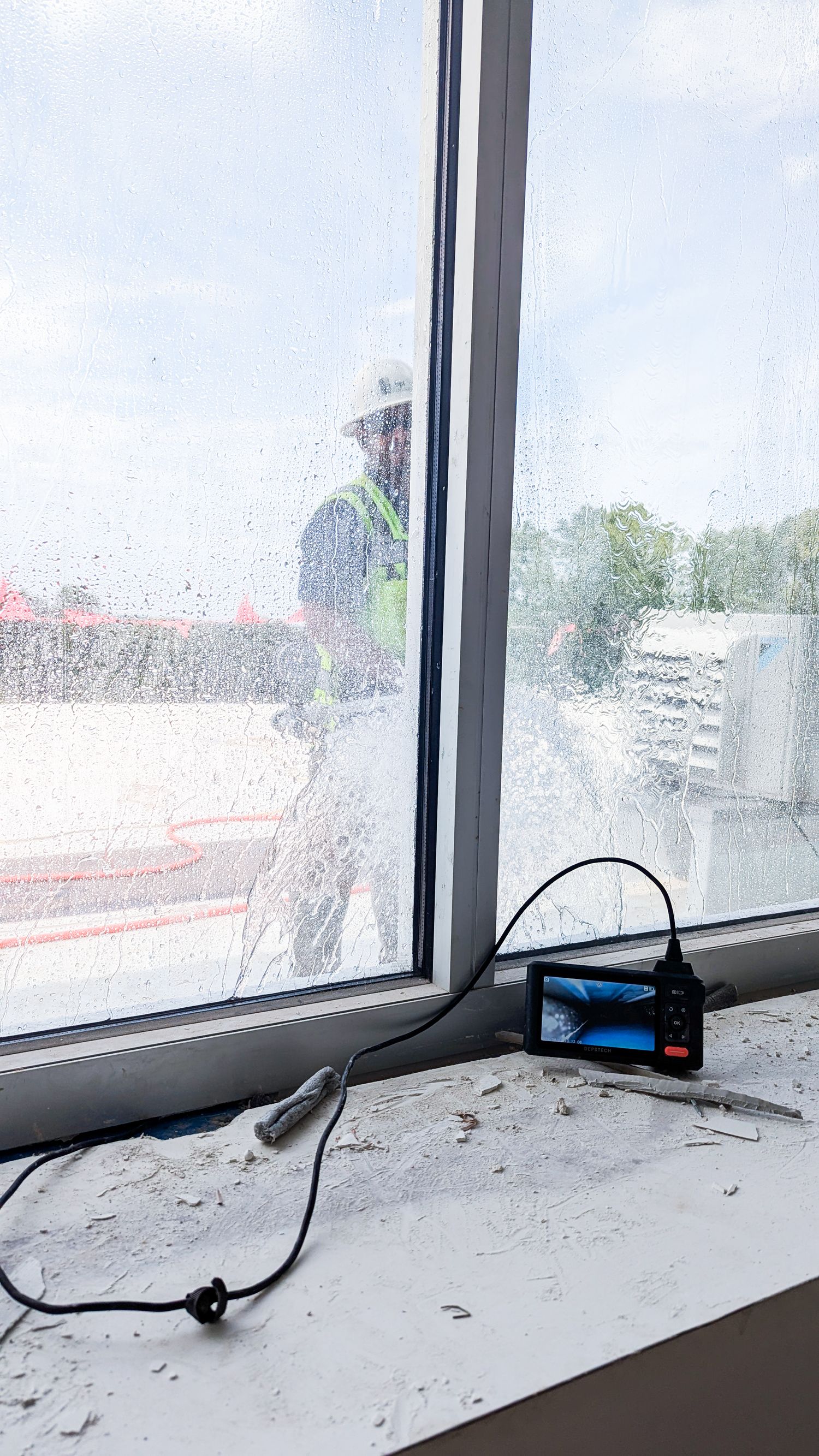 Dusty windowsill with electrical cords and debris visible against cloudy sky view.