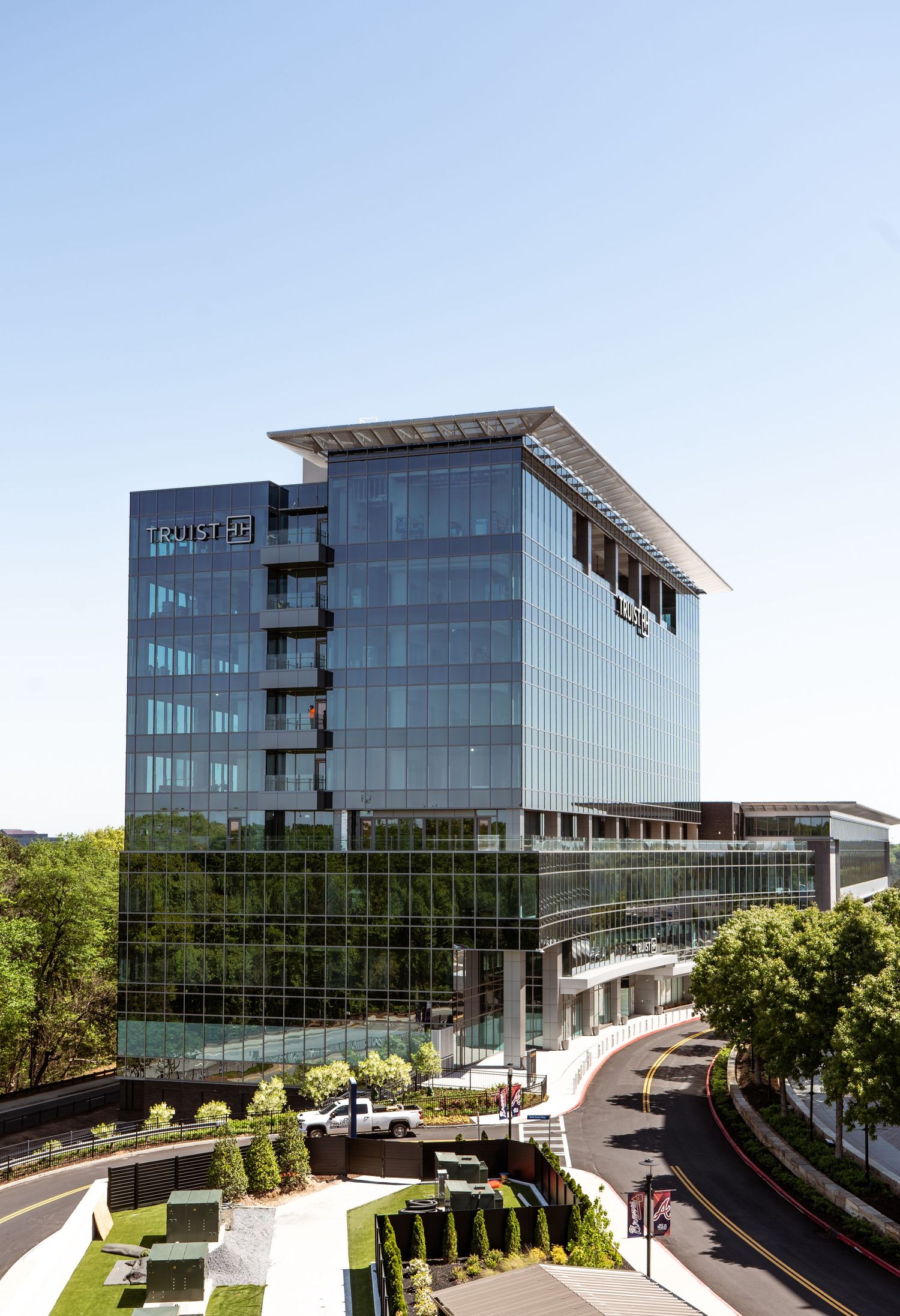 Modern glass office building with curved driveway and landscaped entrance at Techwerks headquarters.