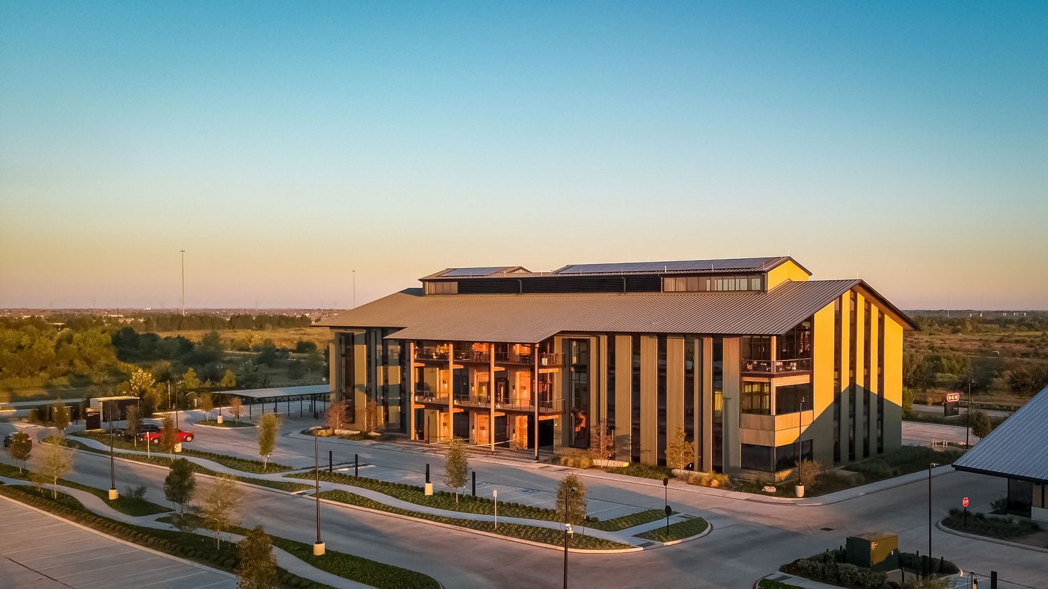 Modern commercial building with wood and metal exterior captured at sunset against a blue sky in an open landscape.