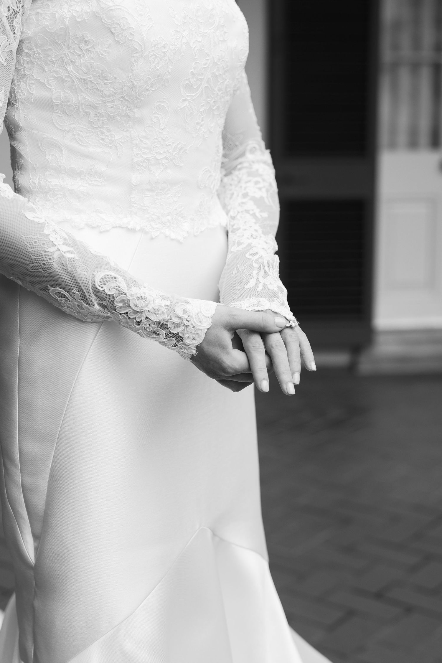 Close-up detail of white lace wedding dress in black and white photography.