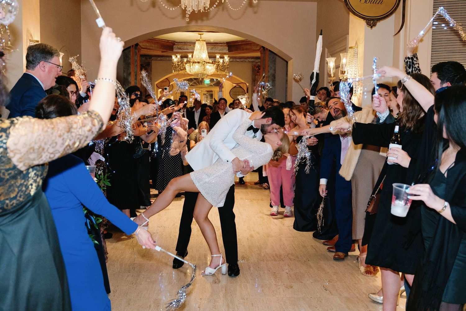 Couples dancing together in an elegant ballroom with chandeliers and formal attire during a social dance event.