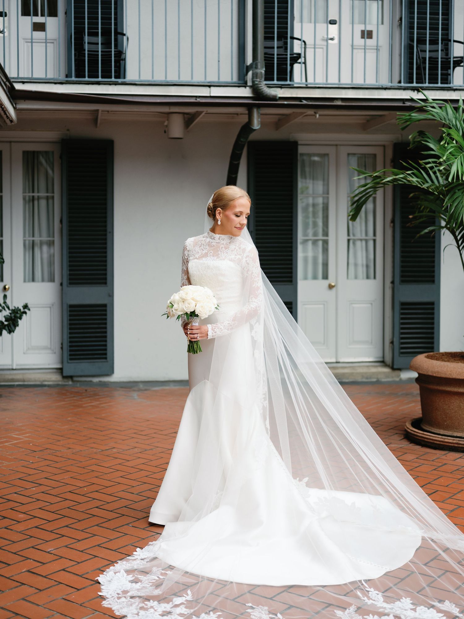 Elegant bridal gown with cathedral-length veil photographed on outdoor terrace.