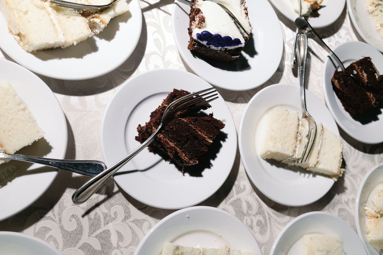 An assortment of wedding cake slices on white plates displayed on a lace tablecloth.