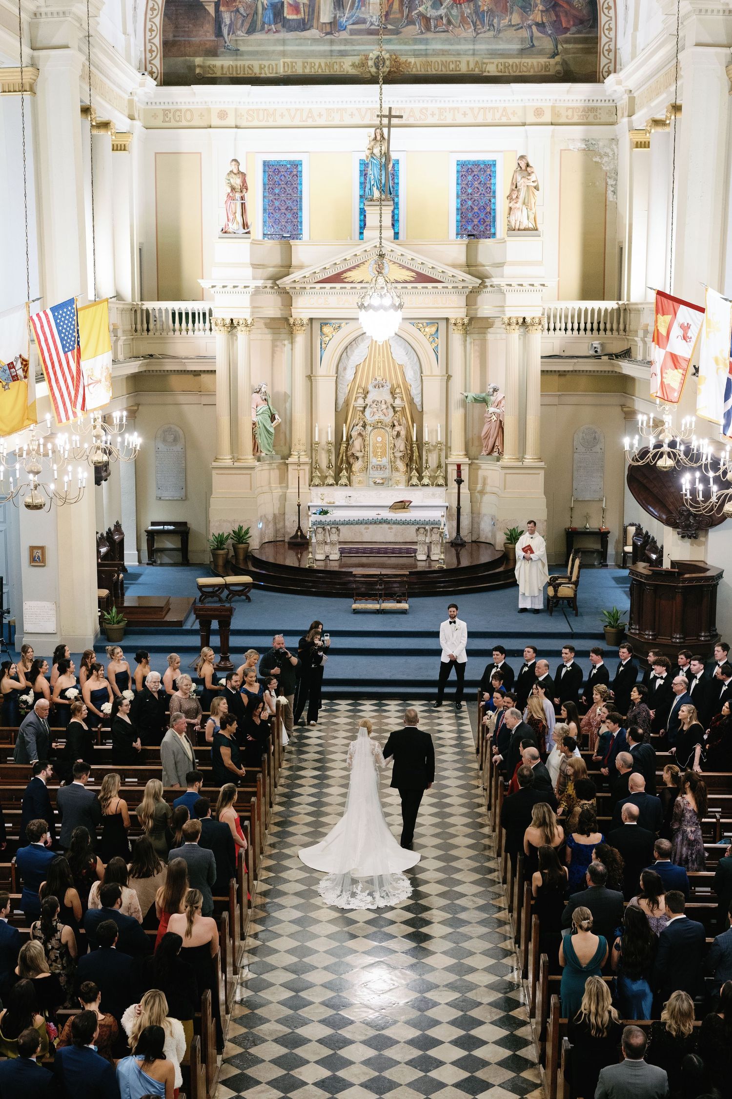 Overhead view of wedding ceremony in ornate church with checkered floor and painted murals.