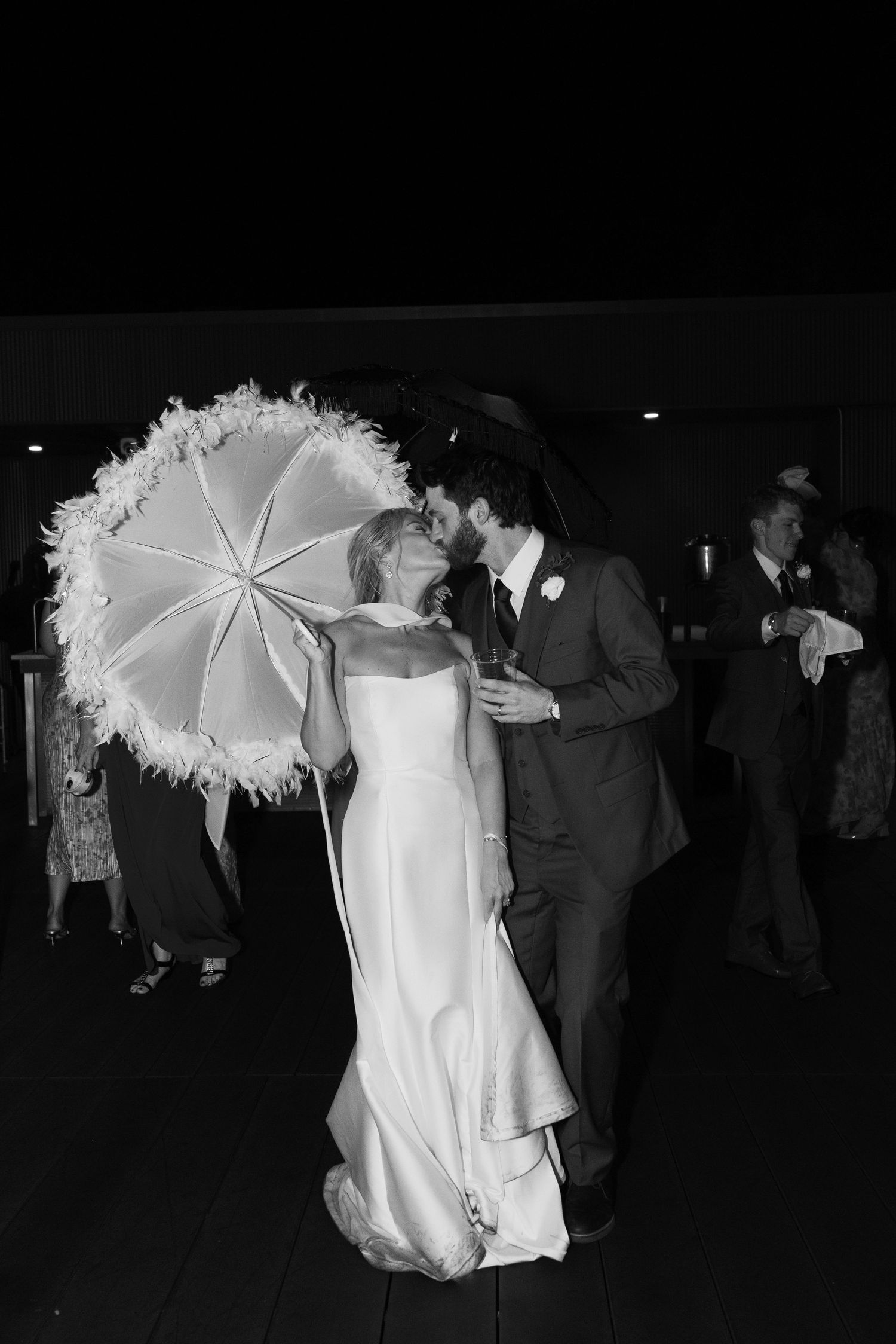 Wedding party with decorative white parasols dancing at evening reception.
