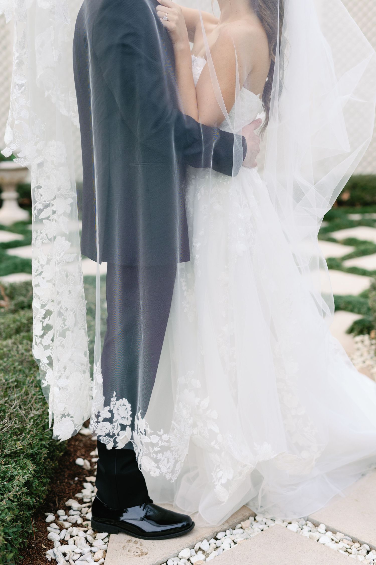 Close-up detail of bride and groom's feet on white petal-covered path.