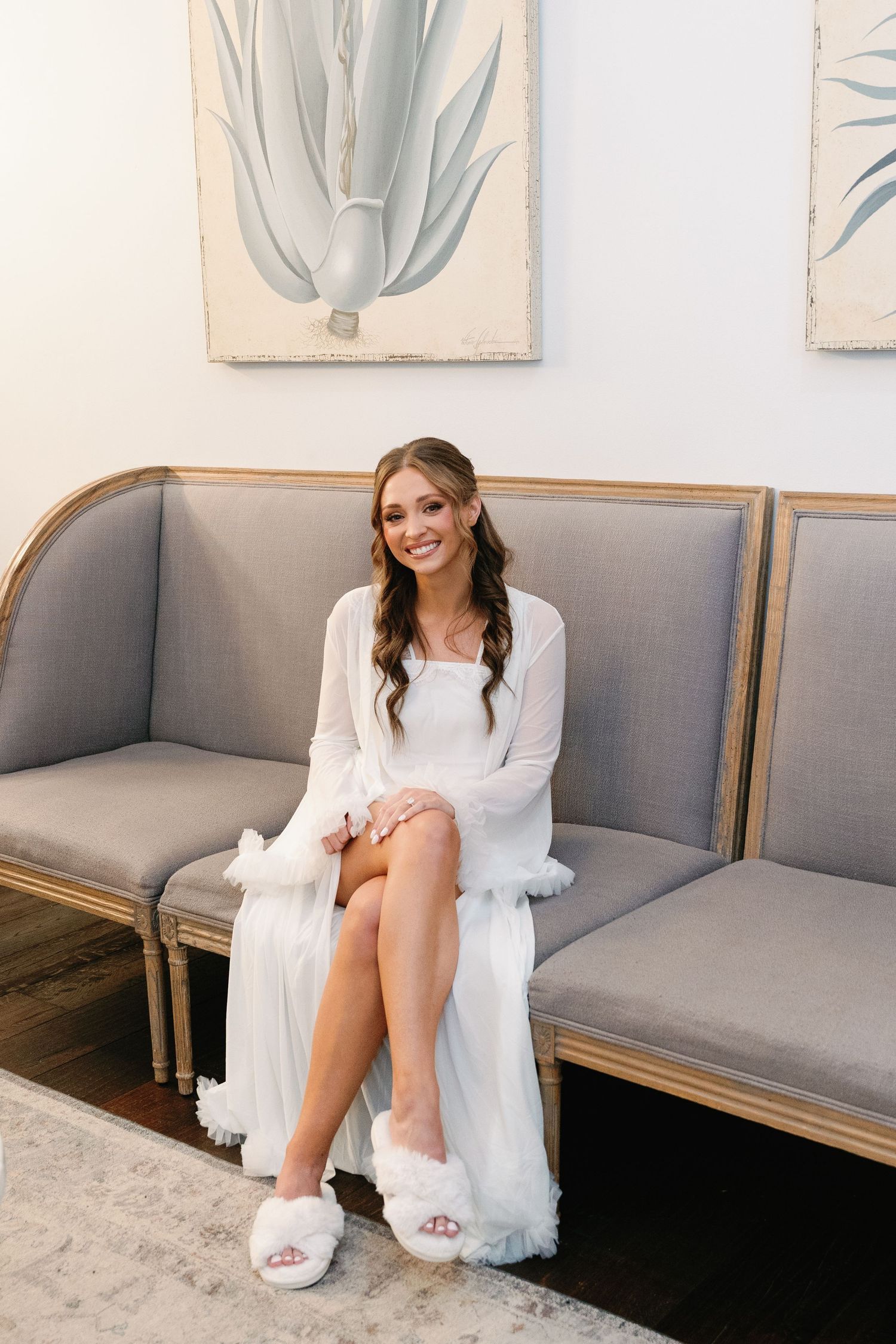 Wedding preparation scene showing white robe and slippers on grey couch.