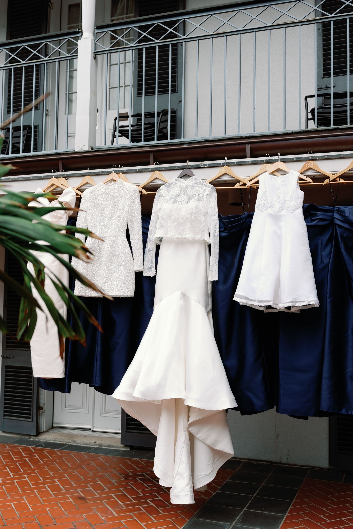 Wedding attire and dresses hanging on a clothesline against white colonial architecture.