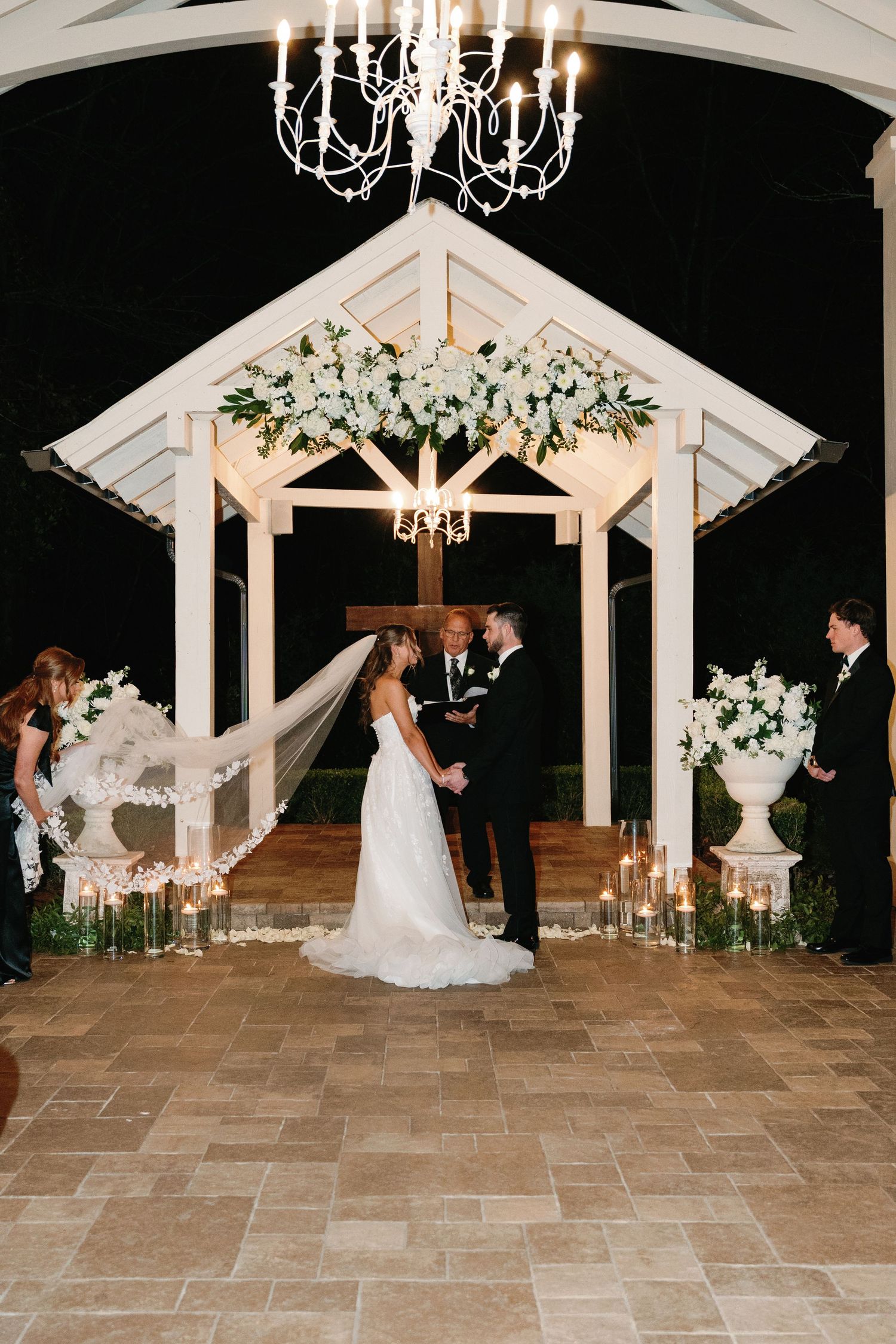 A sequence of nighttime wedding ceremony photos under an illuminated white gazebo with elegant chandeliers and floral decor.