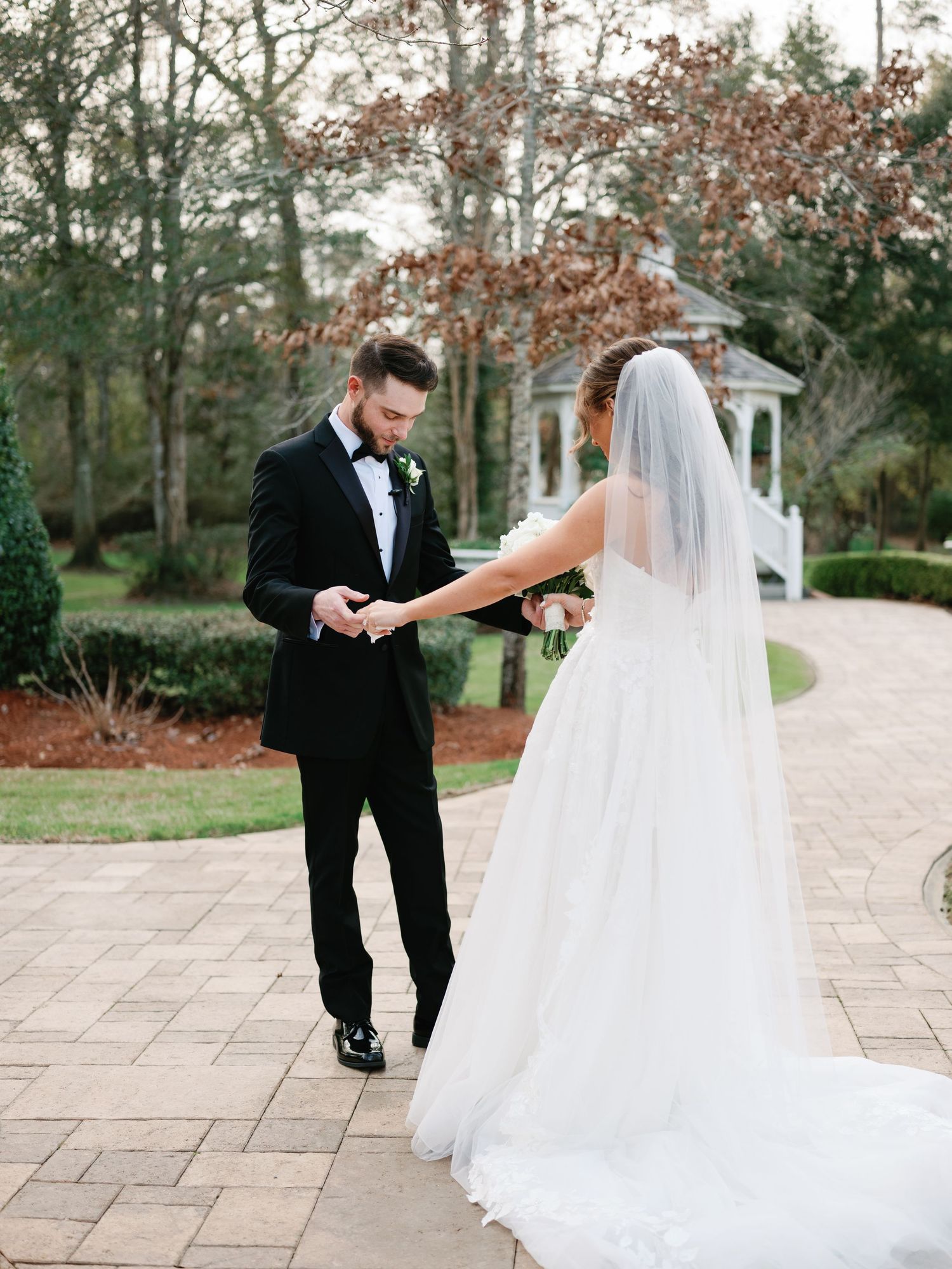 Wedding couple shares romantic first look moment on stone patio surrounded by autumn trees.