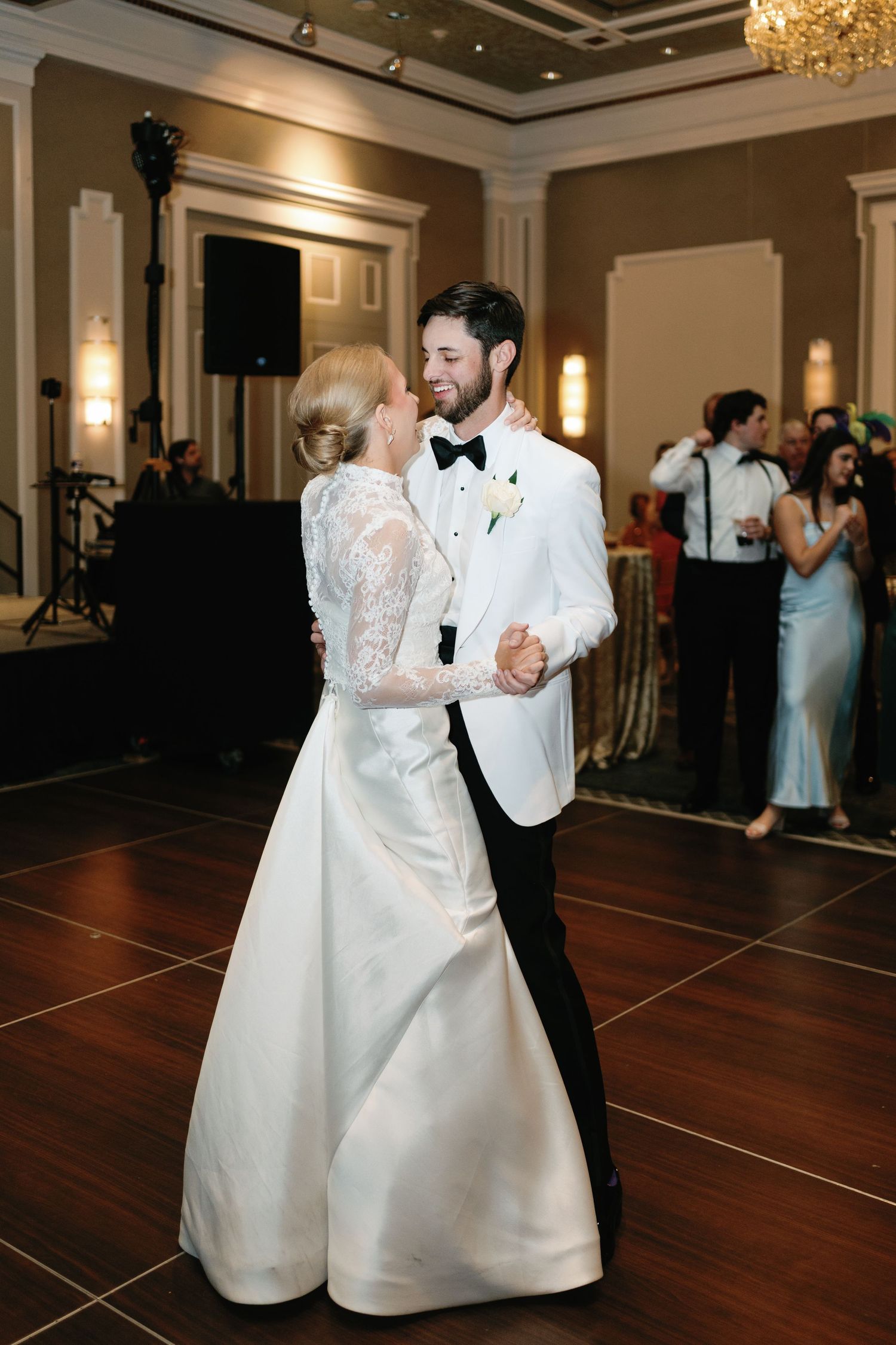 First dance at an elegant wedding reception with chandelier and hardwood dance floor.