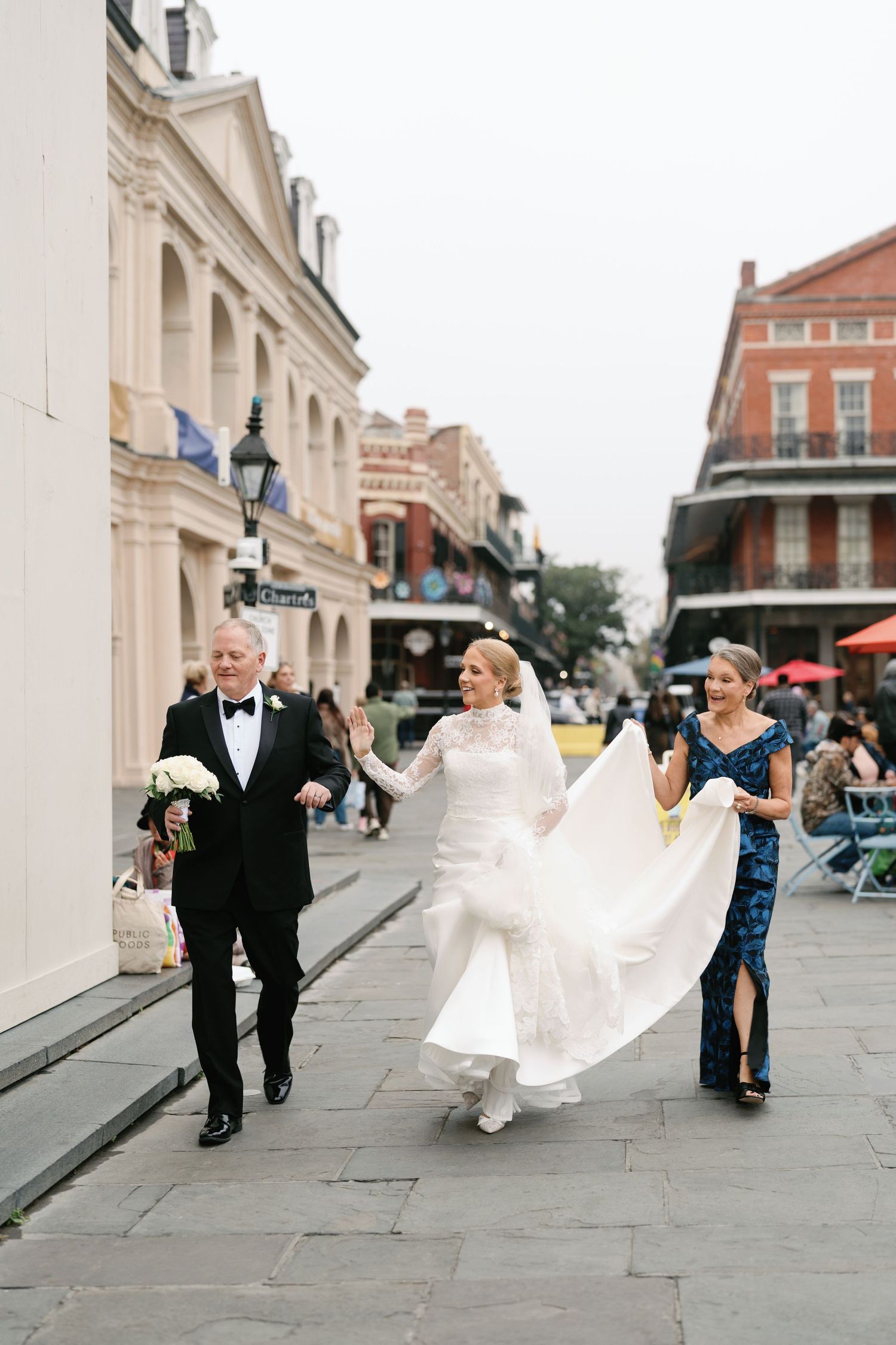 Wedding party walking down historic New Orleans street with bride's dress flowing in the wind.