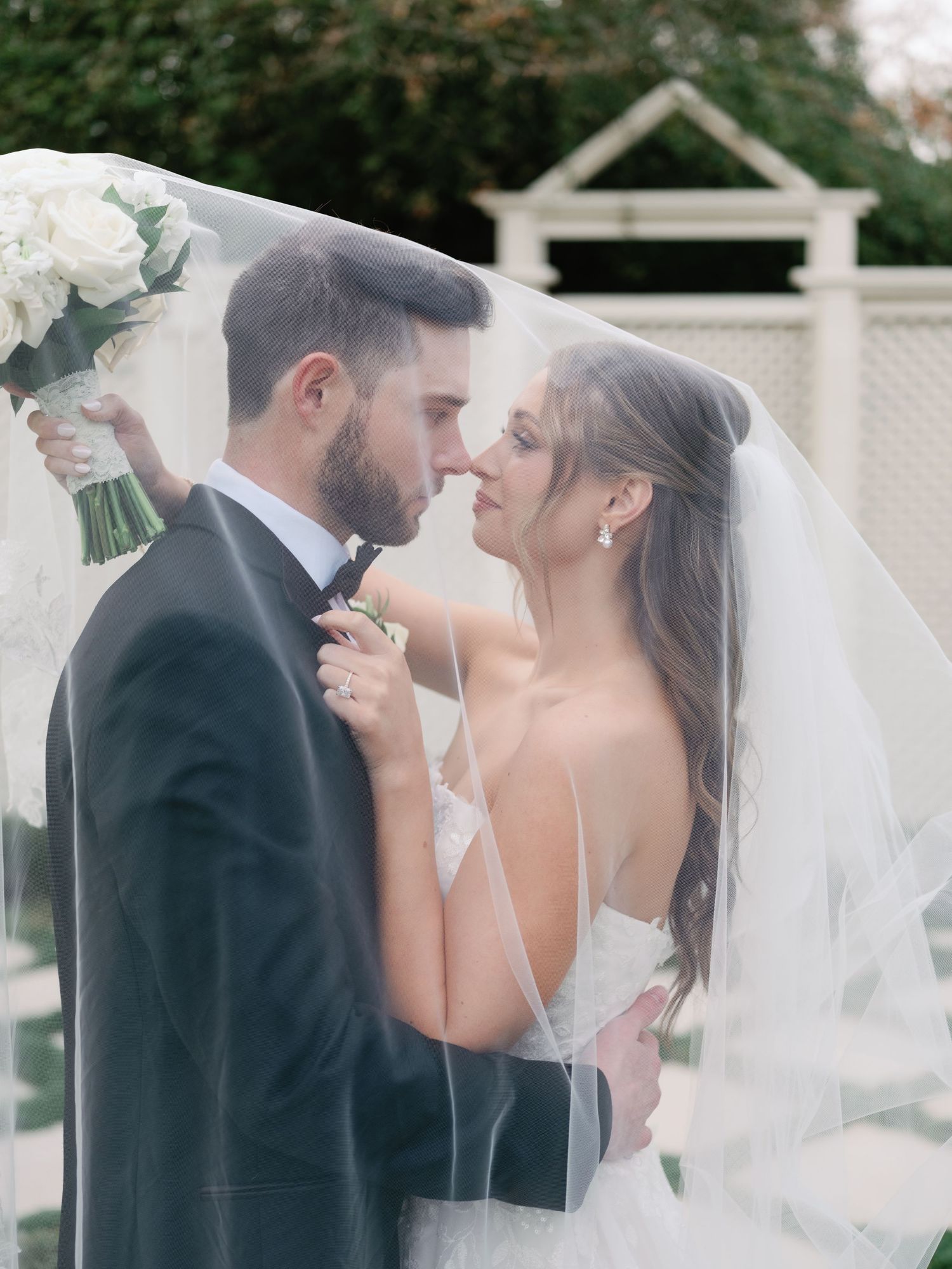 Elegant wedding portraits showing tender moments between newlyweds with bride in white dress and flowing veil.