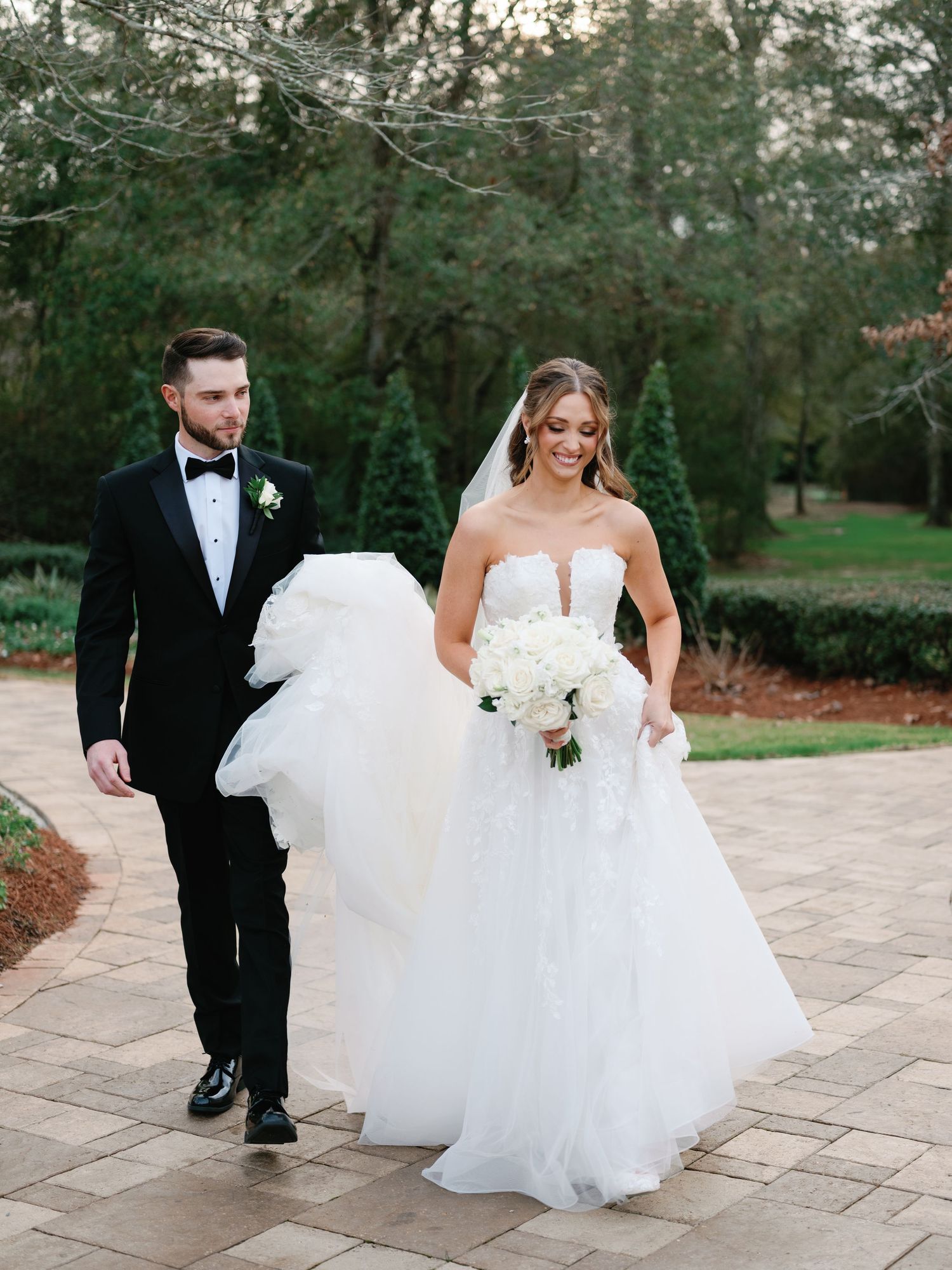 Couple walking on stone patio with flowing white wedding dress.