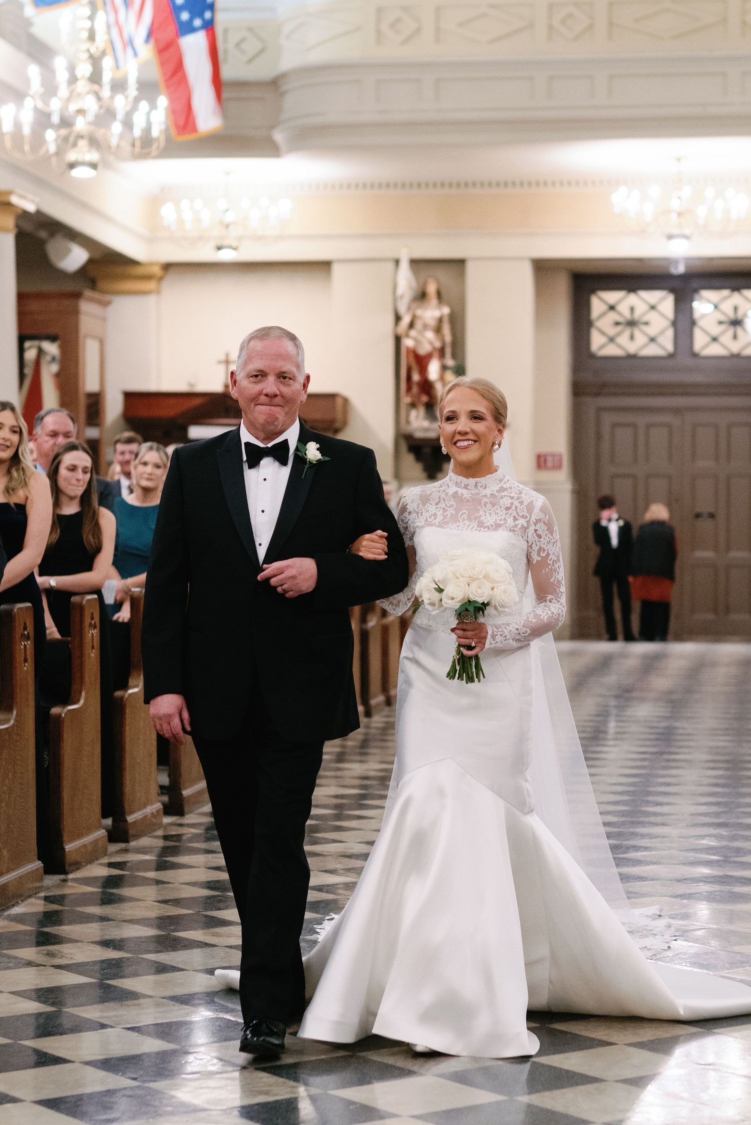 Wedding ceremony processional in an elegant church with black and white checkered floor.