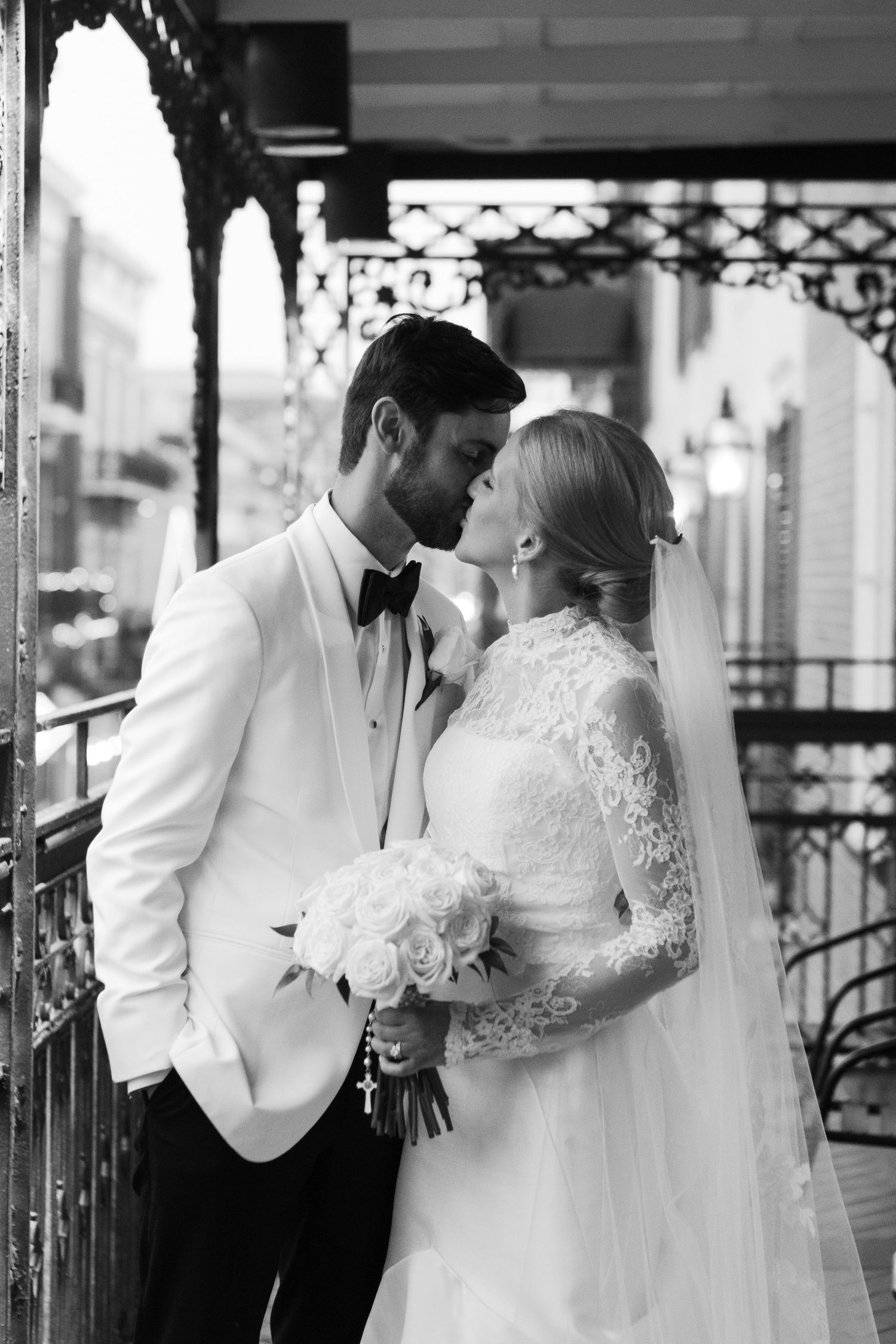 Elegant black and white wedding portraits taken on a vintage-style covered balcony.