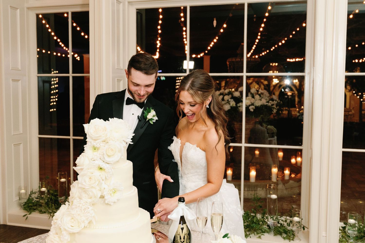 A wedding reception venue with twinkling lights and elegant decor visible through large windows.