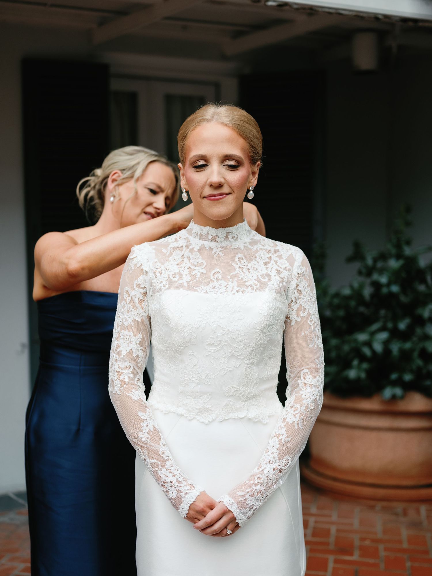 A bride in a long-sleeved lace wedding dress with delicate details is photographed from multiple angles.