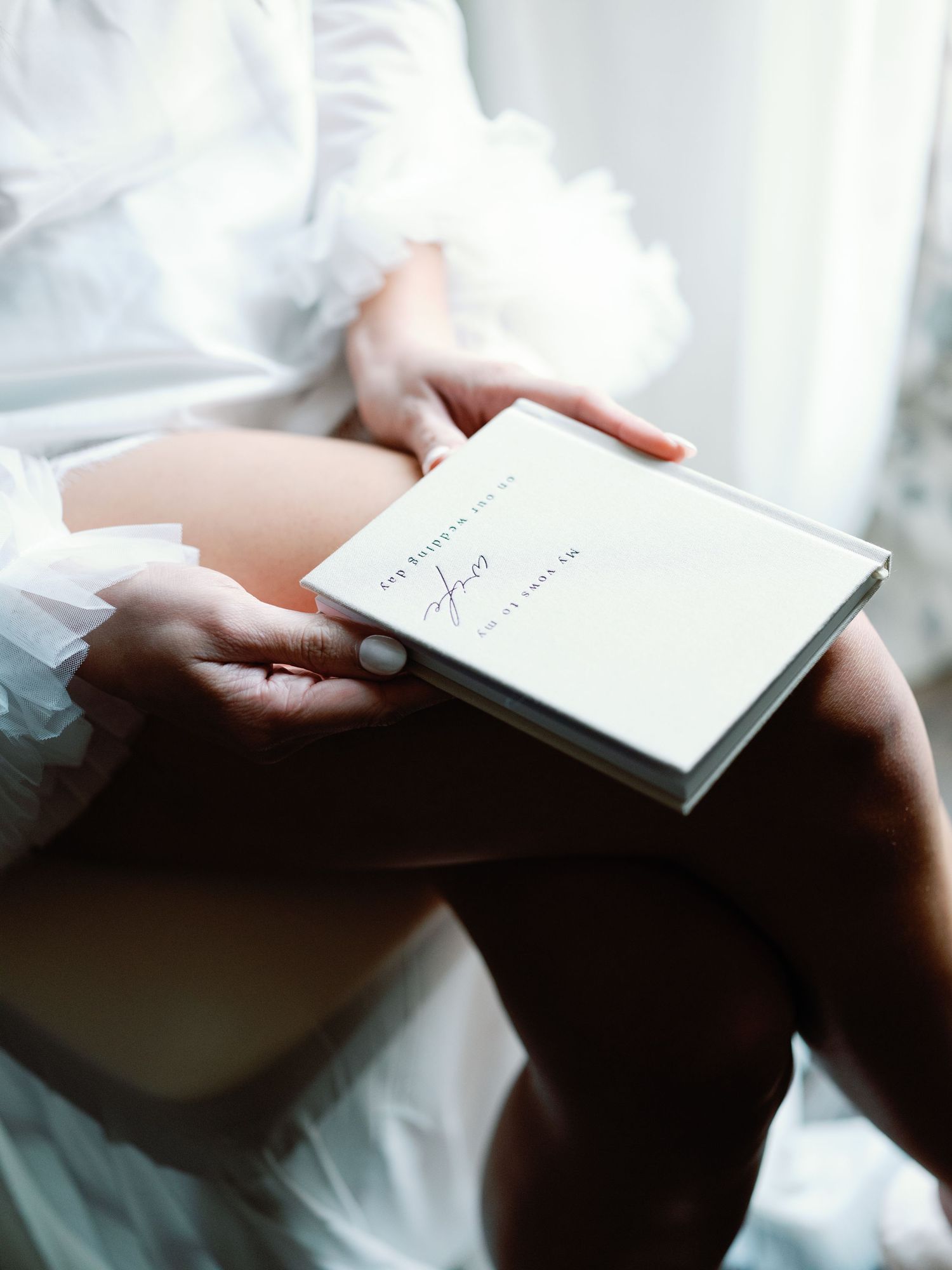 Hands delicately holding a small white note card or letter against a light background.