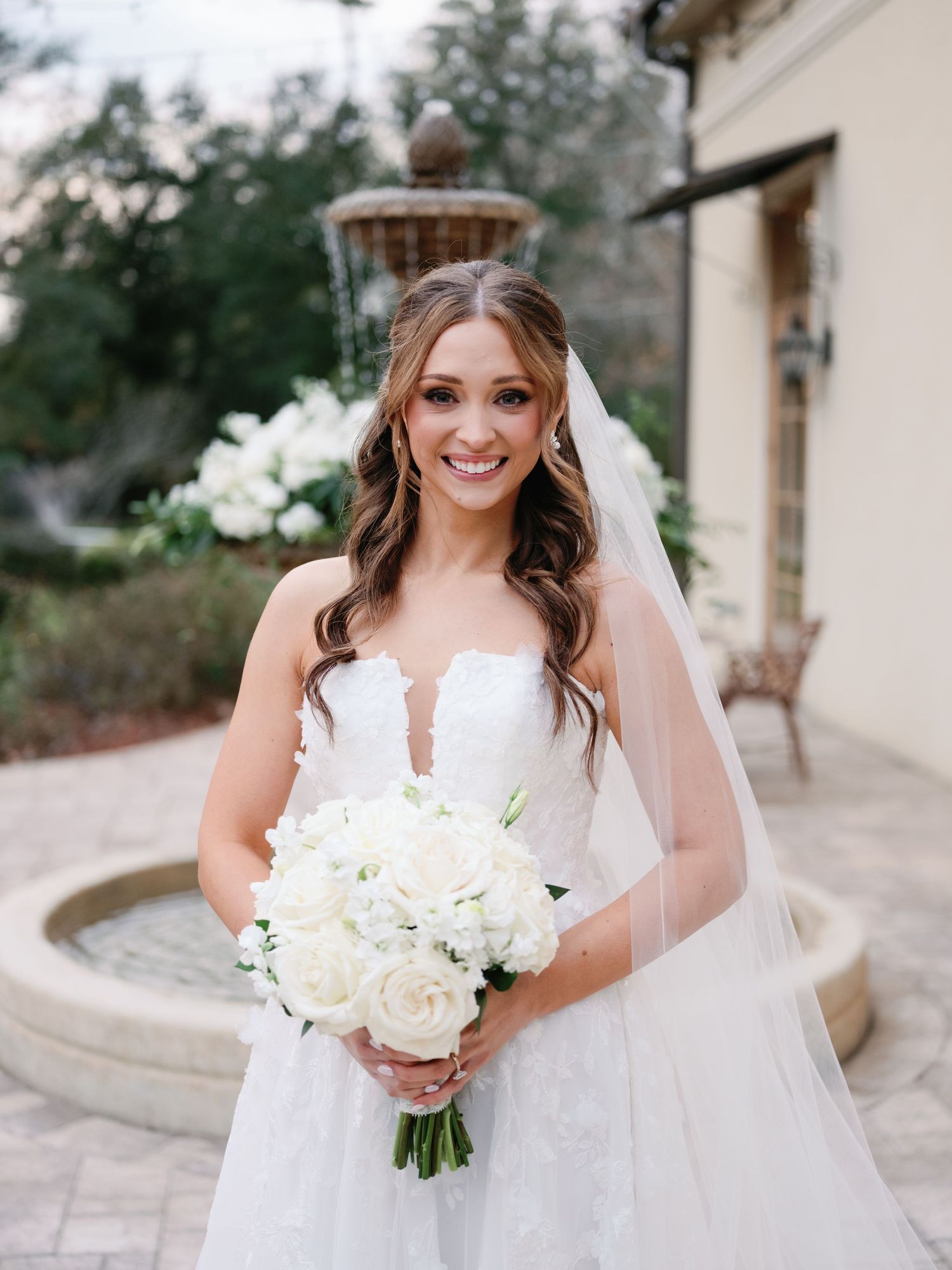 Joyful bridal portraits featuring white wedding gown, flowing veil and classic white rose bouquet.